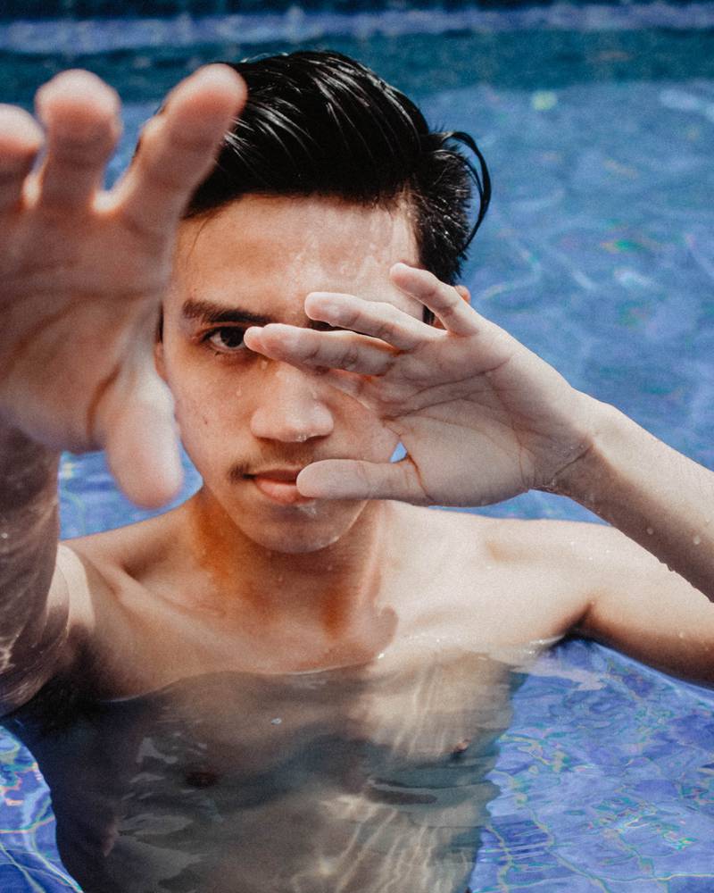 Homem dentro da piscina mostrando as mãos