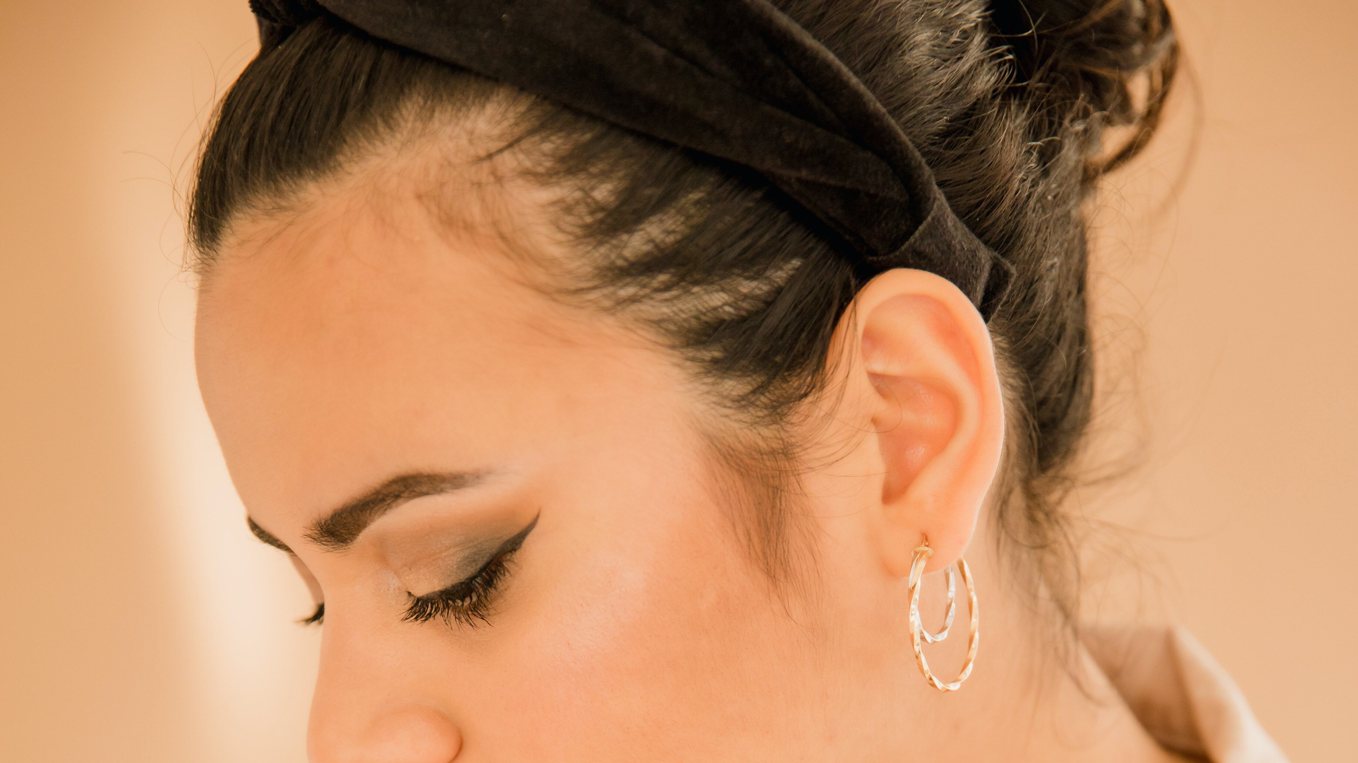 Mulher branca segurando frasco de perfume verde próximo ao pescoço