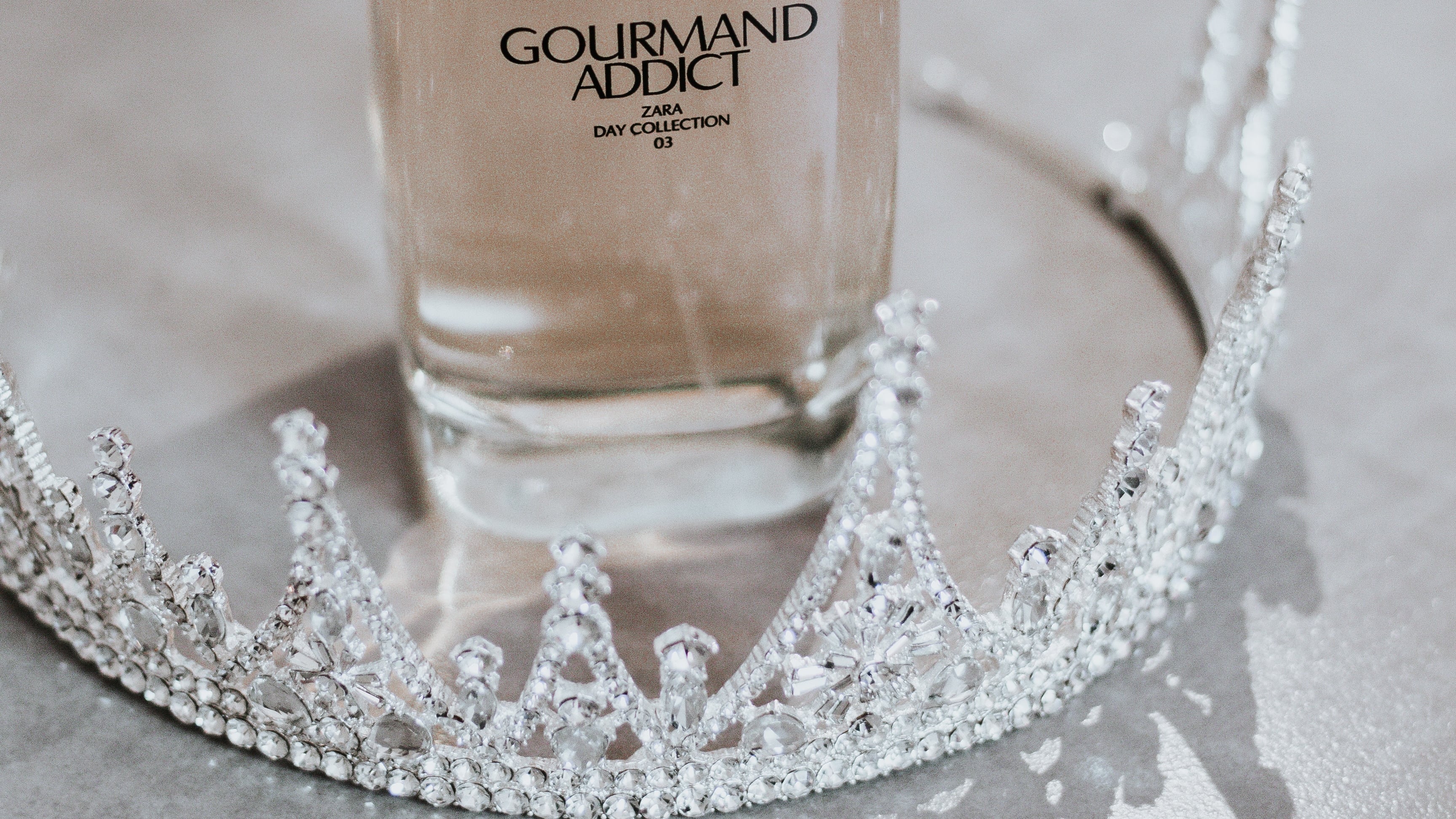 Frasco de perfume ao lado de coroa