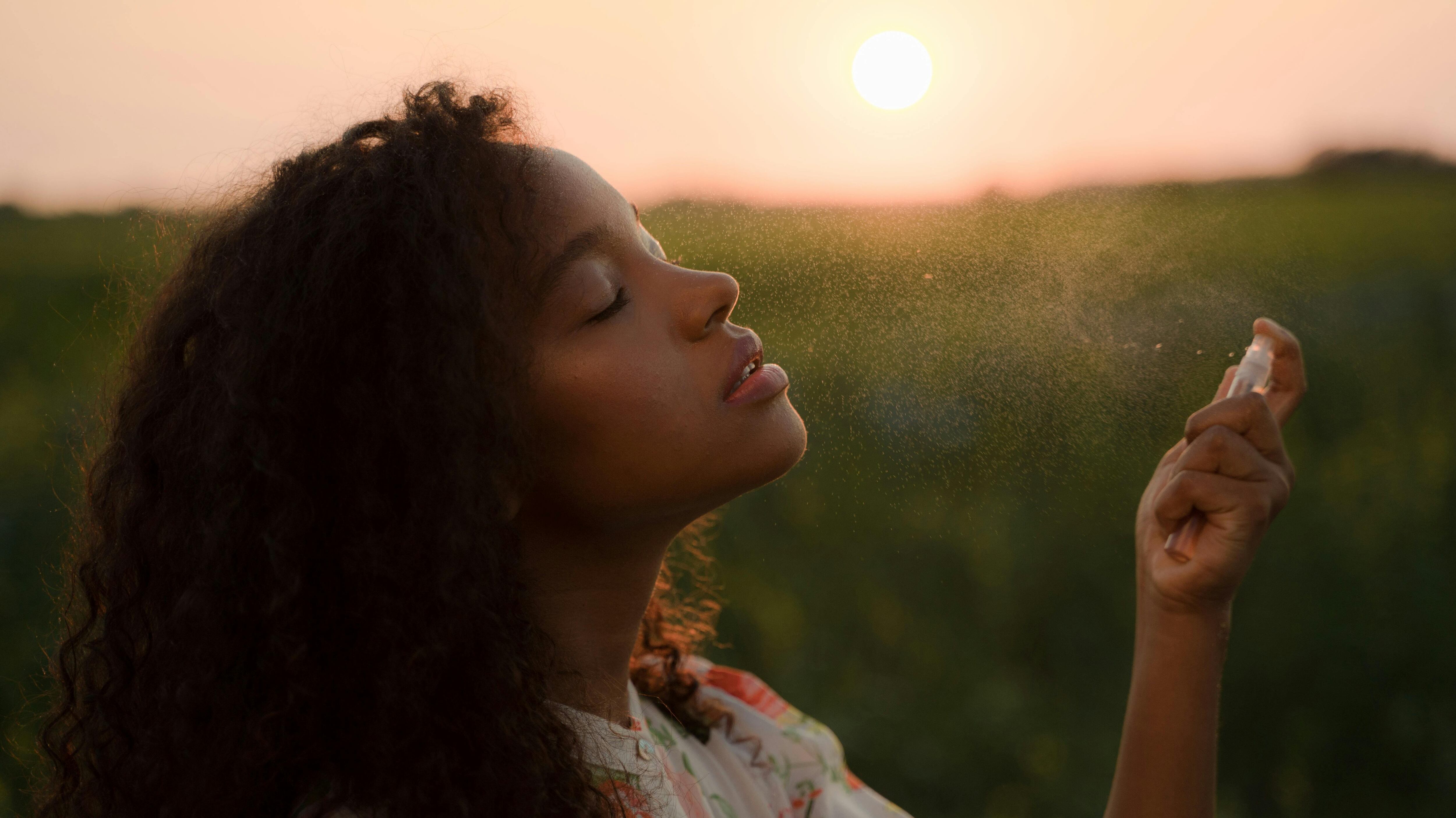Mulher negra espirrando frasco de perfume