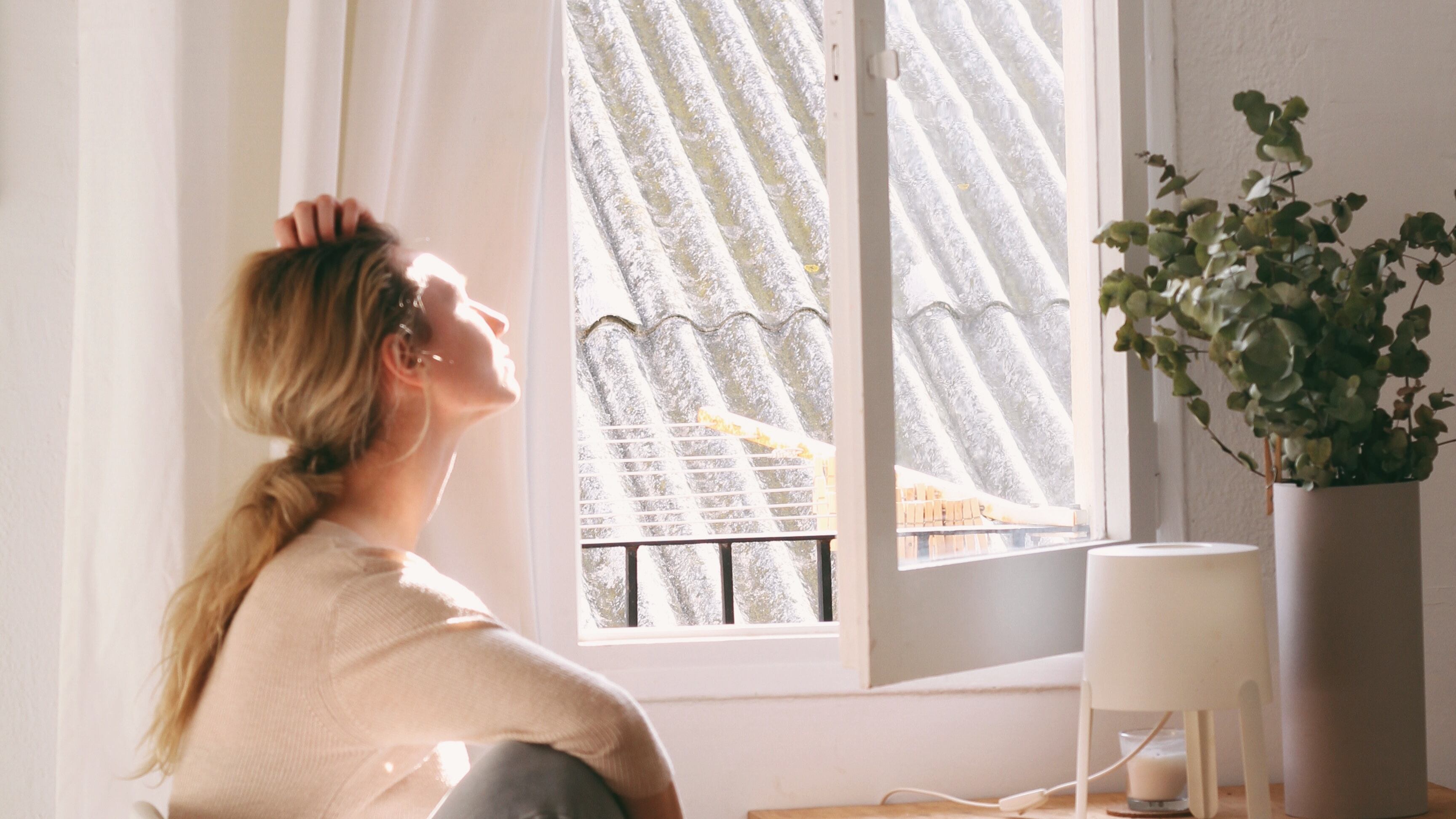 Mulher tomando sol na janela
