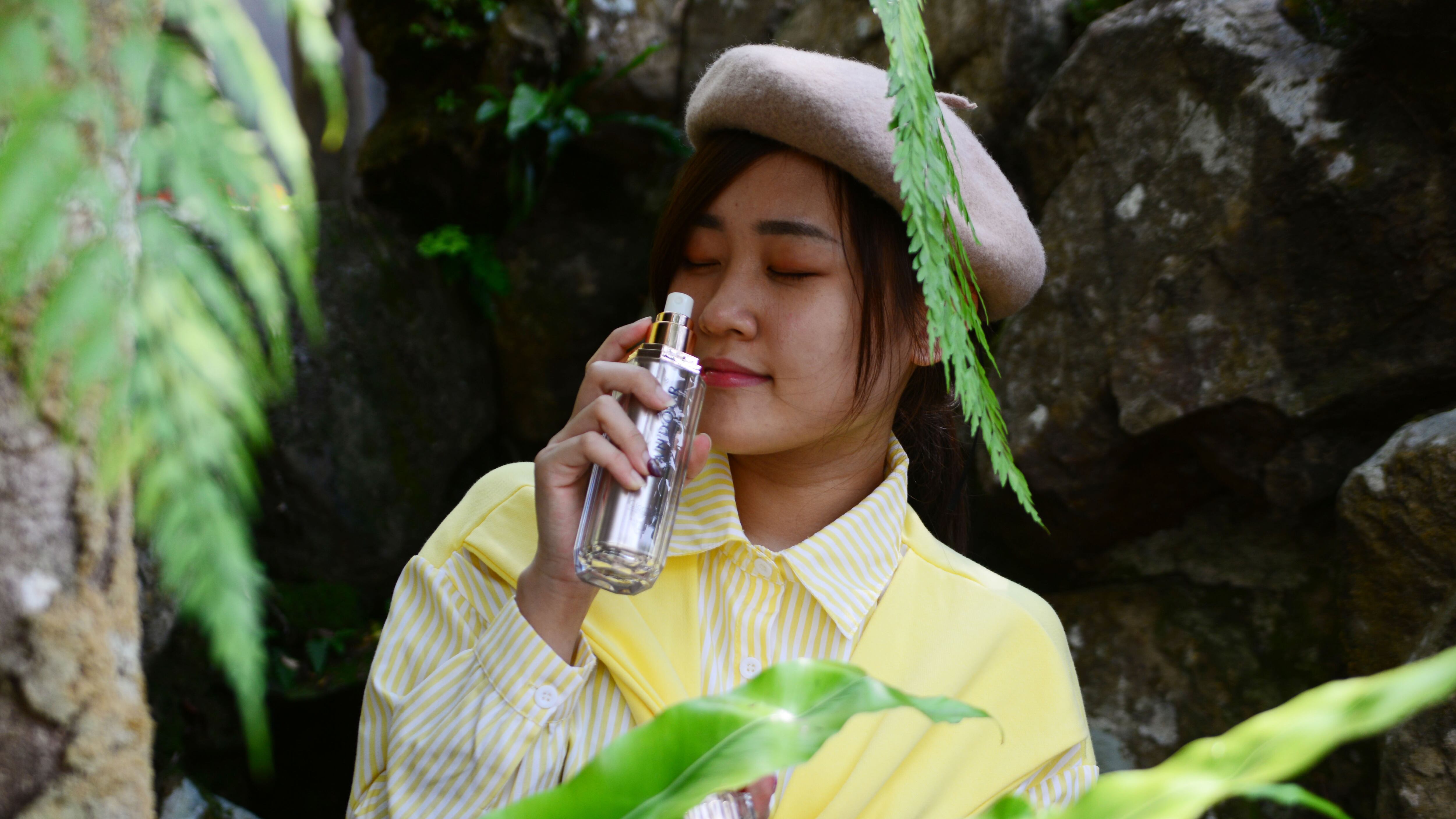 Mulher asiática segurando spray de perfume