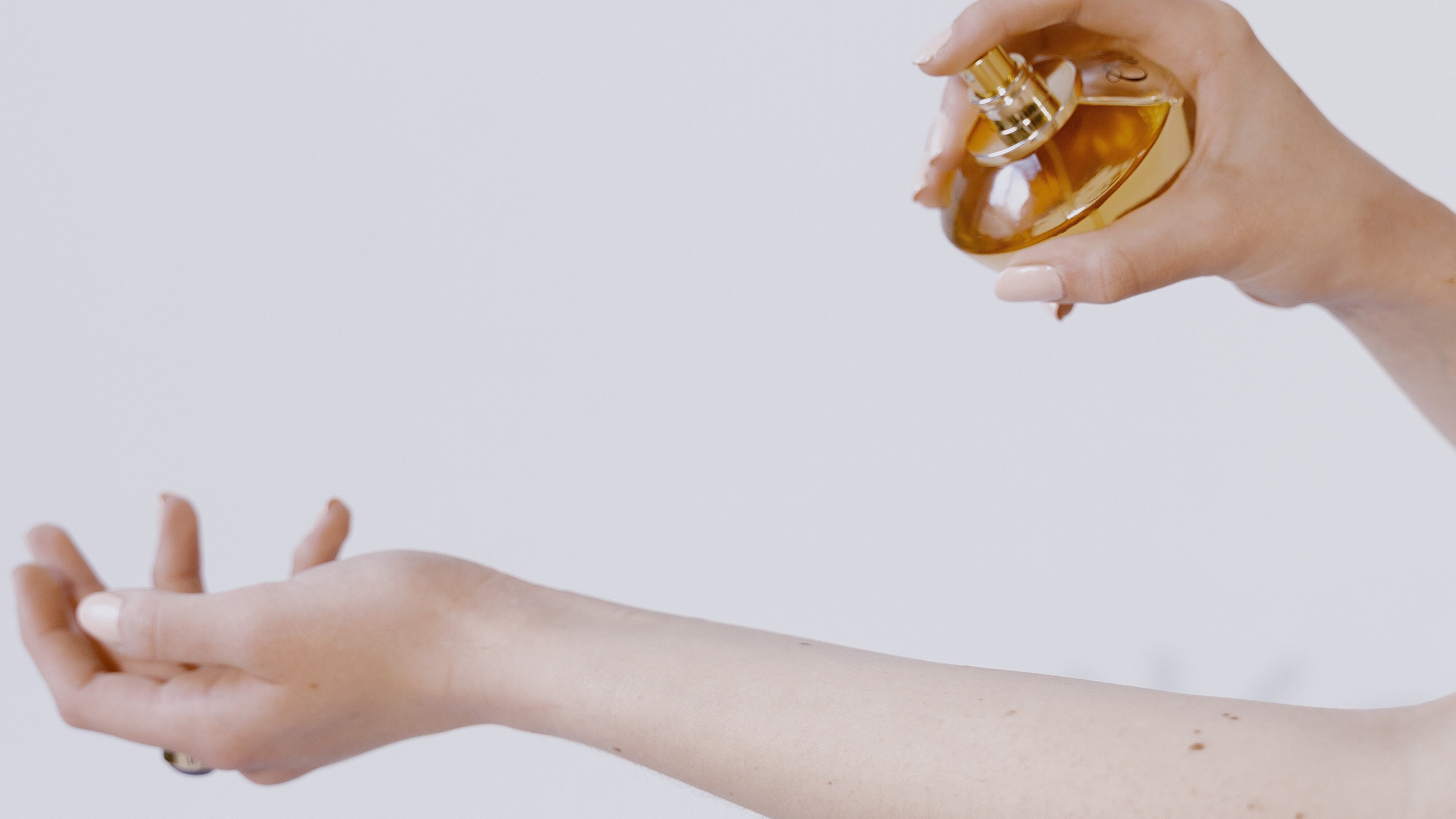 Mulher passando perfume no braço