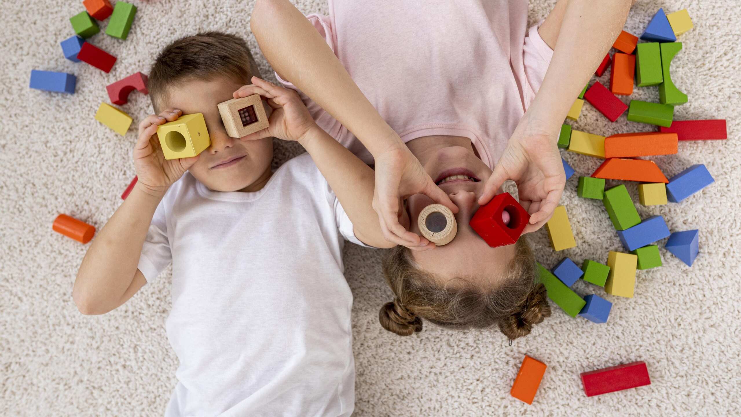 A importância das brincadeiras para o desenvolvimento das crianças; duas crianças brincando com blocos coloridos