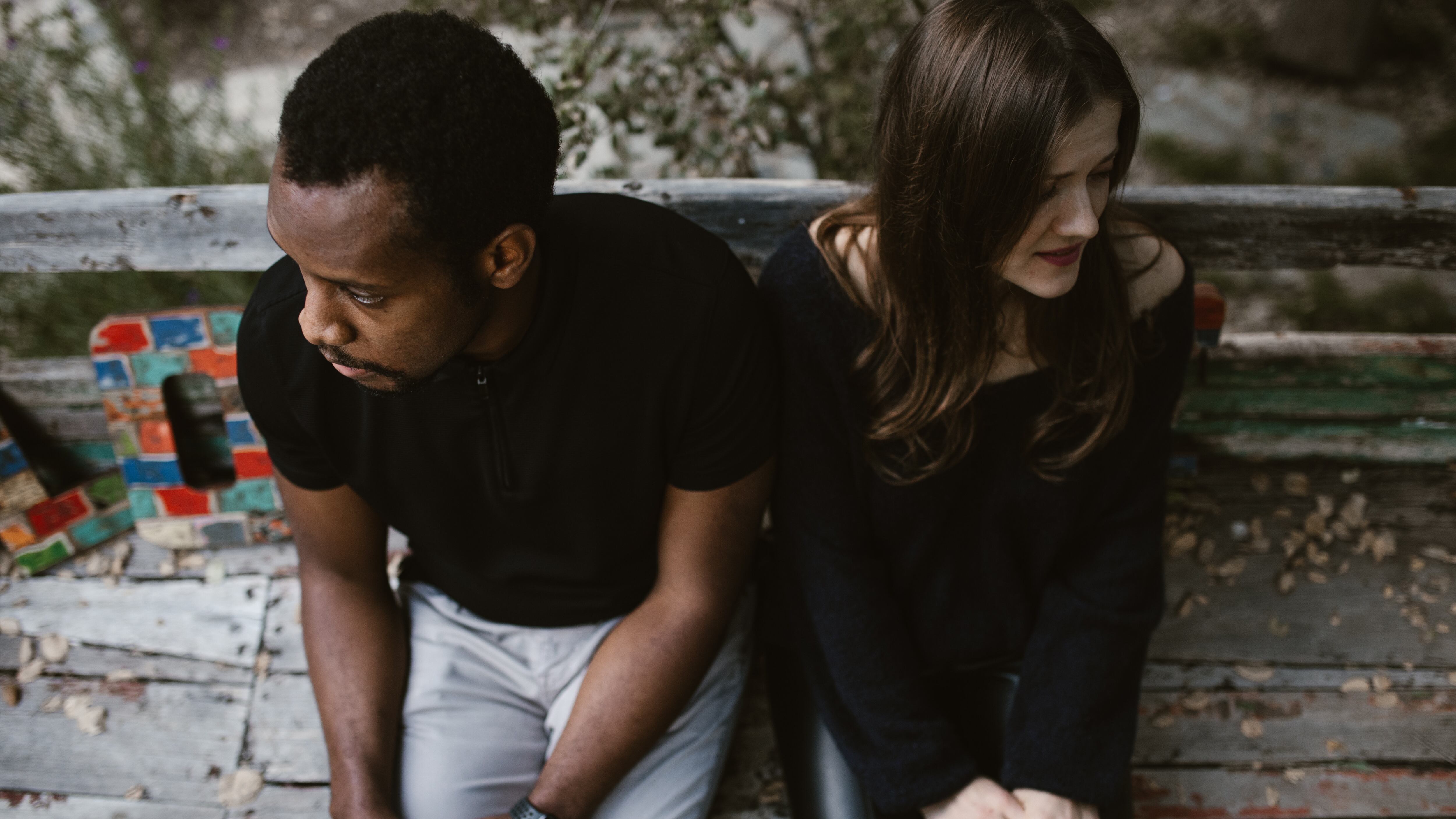 Casal sentado em banco com rostos virados um para o outro