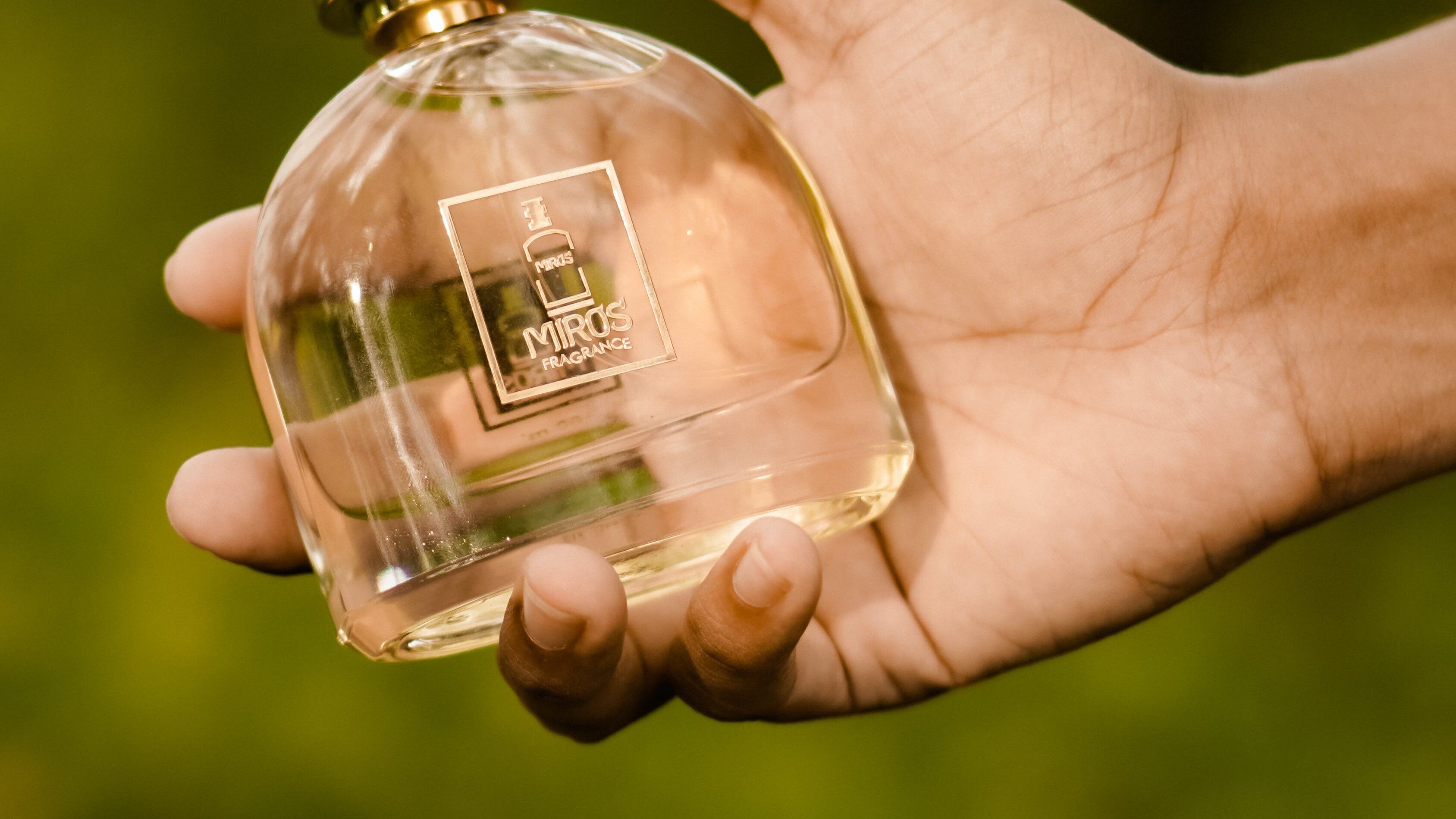 Mão negra masculina segurando frasco de perfume