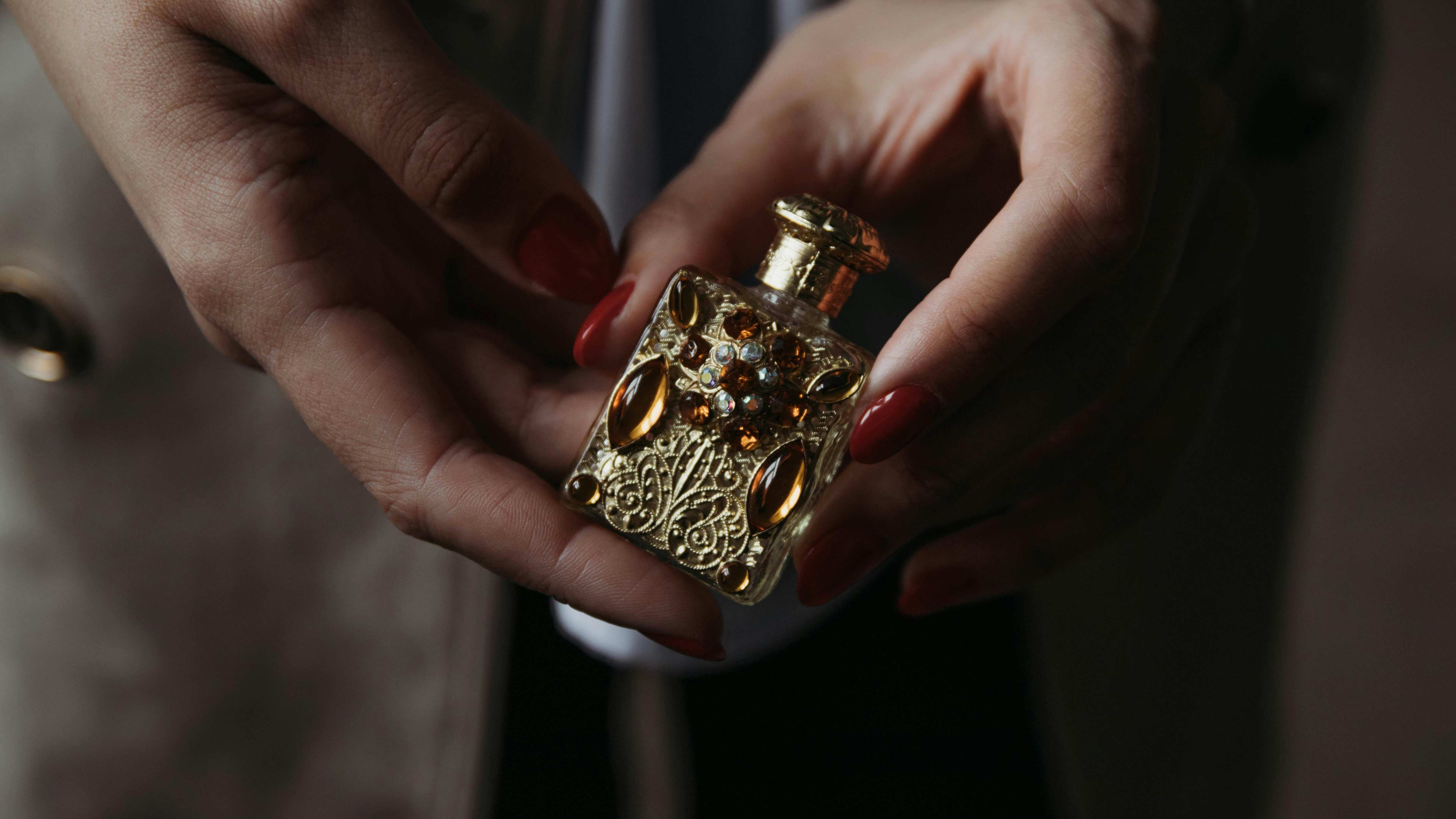 Mãos femininas segurando frasco de perfume