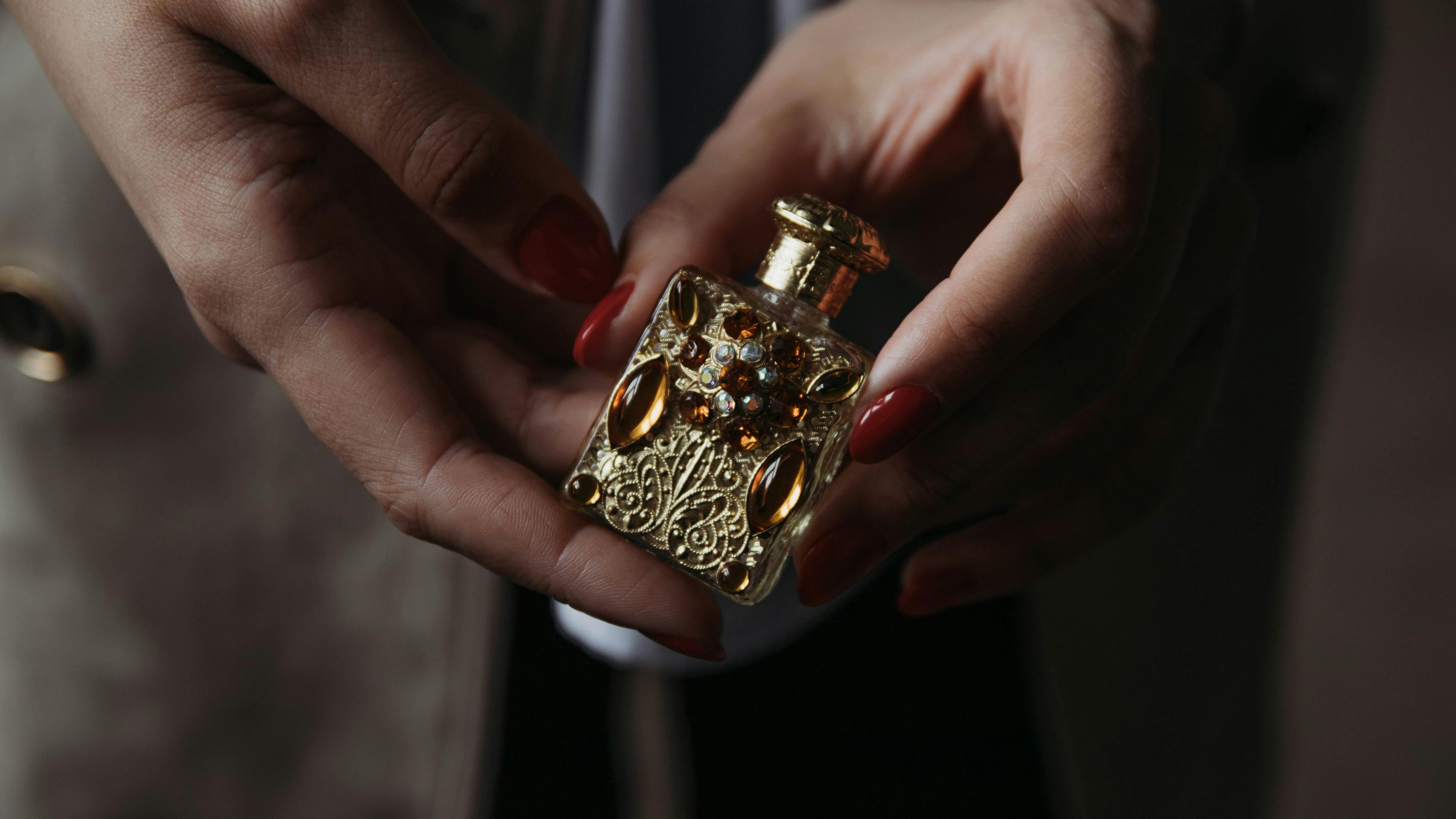 Mãos femininas segurando frasco de perfume