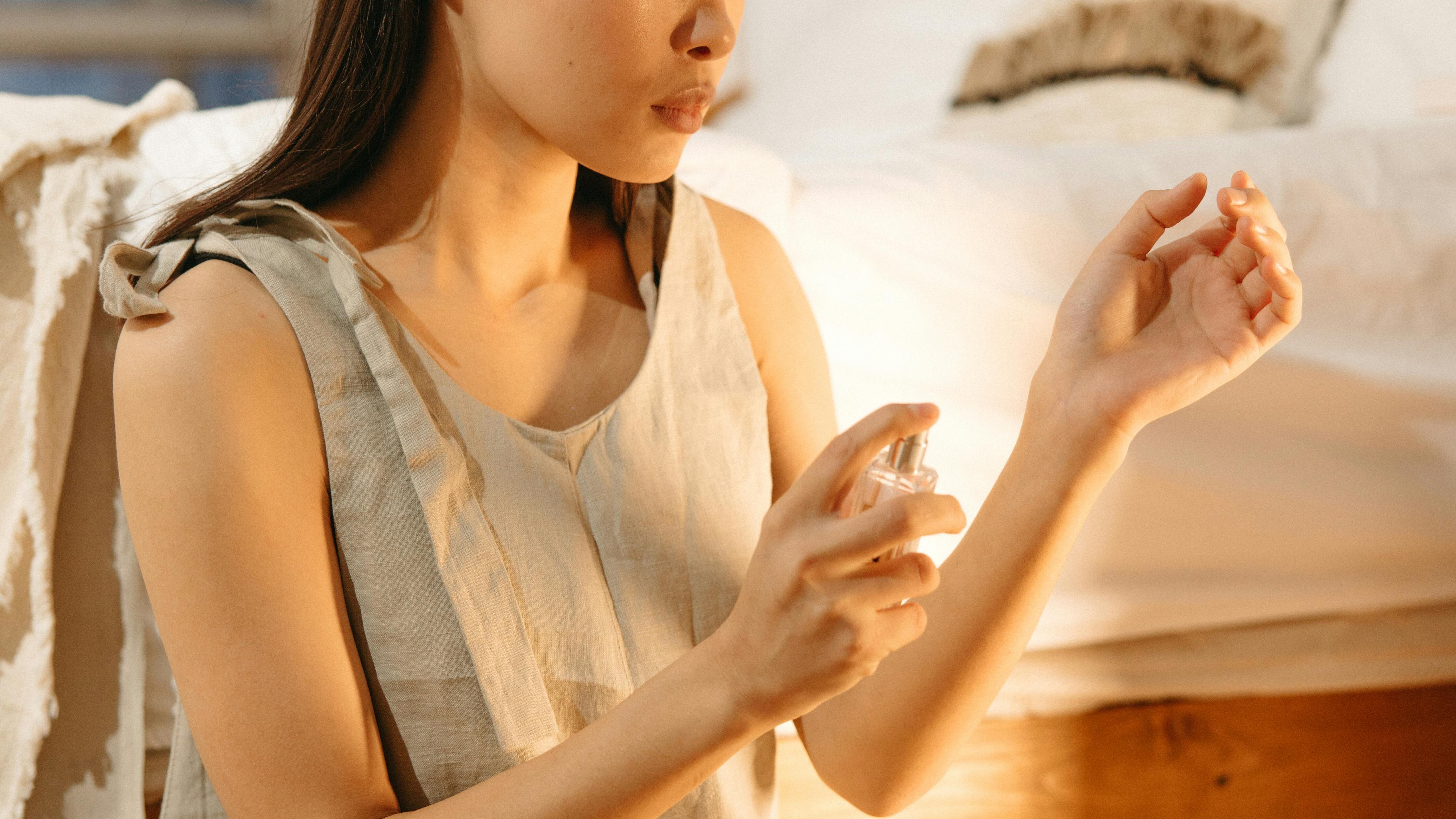 Mulher asiática borrifando perfume no braço