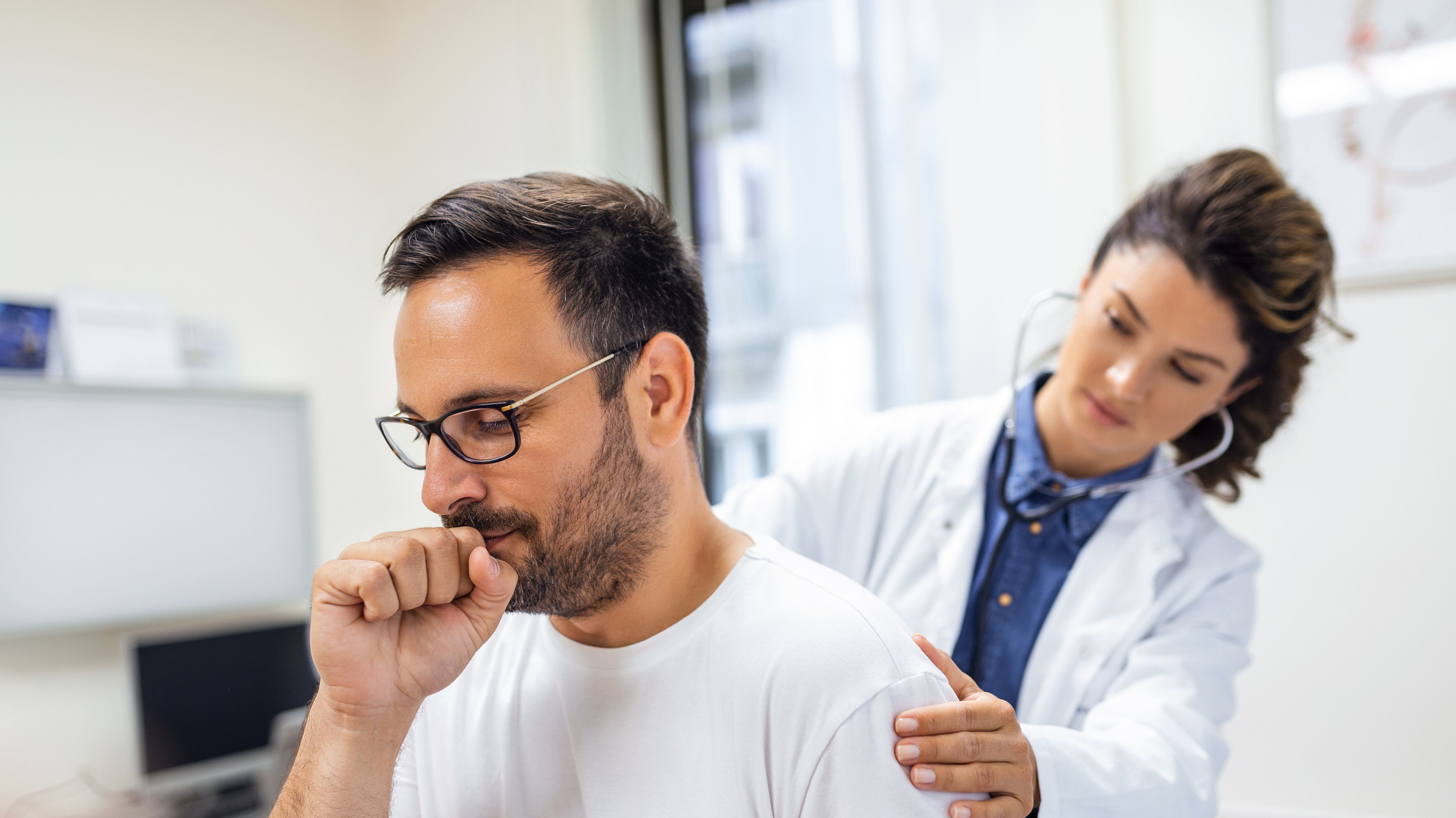 Homem tossindo enquanto médica o consulta