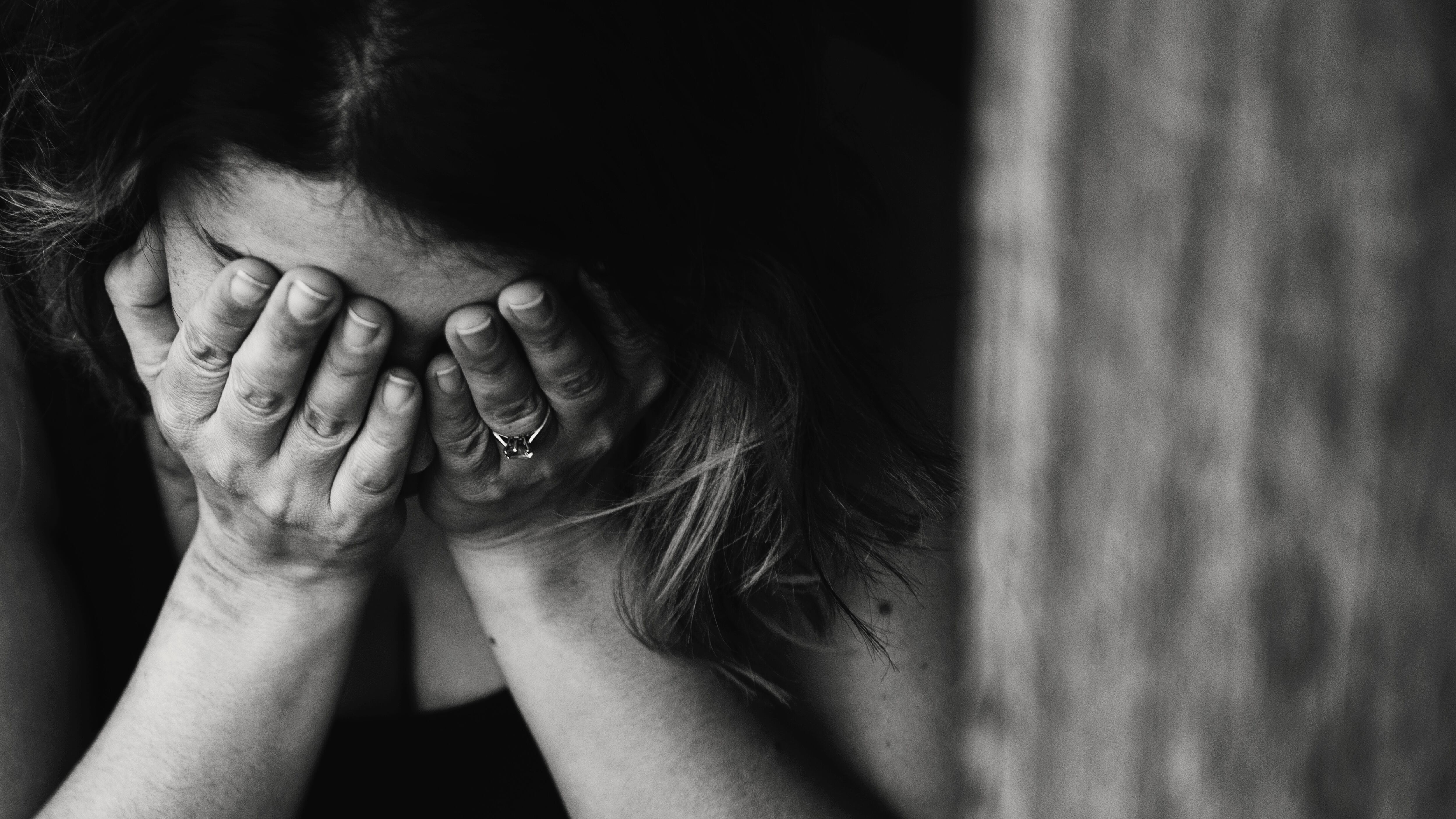 Imagem em preto e branco de mulher com mãos sobre o rosto