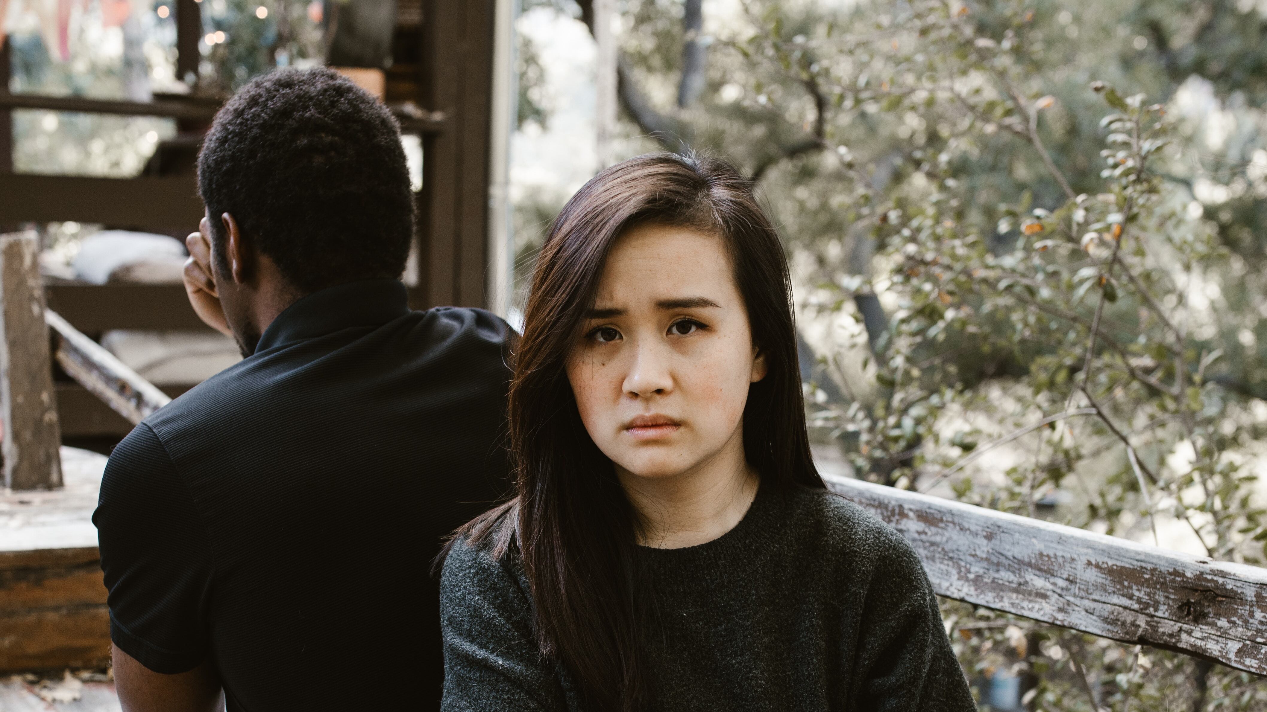 Mulher asiática sentada no banco de costas para namorado negro