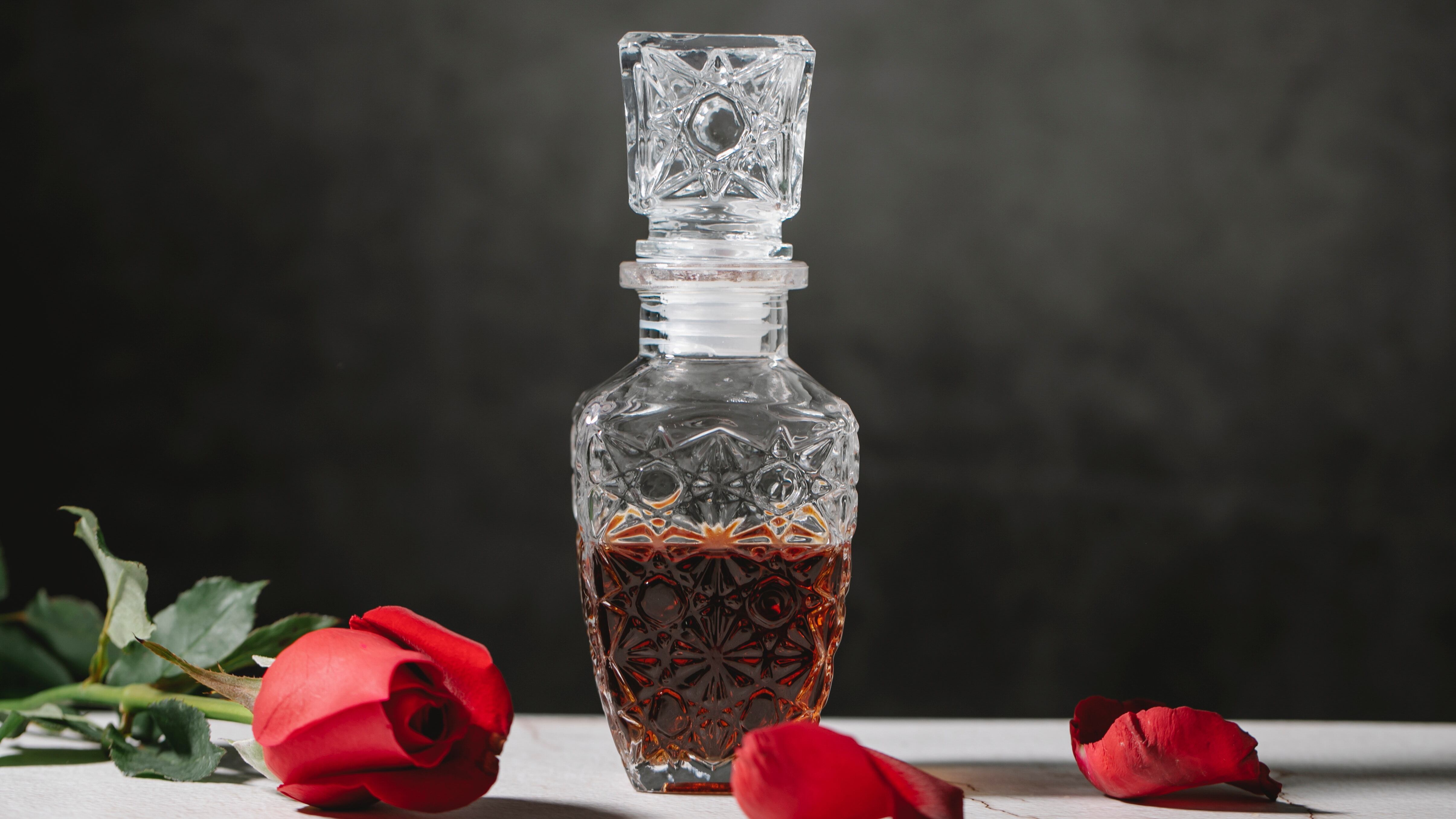 Frasco de perfume antigo ao lado de flor vermelha