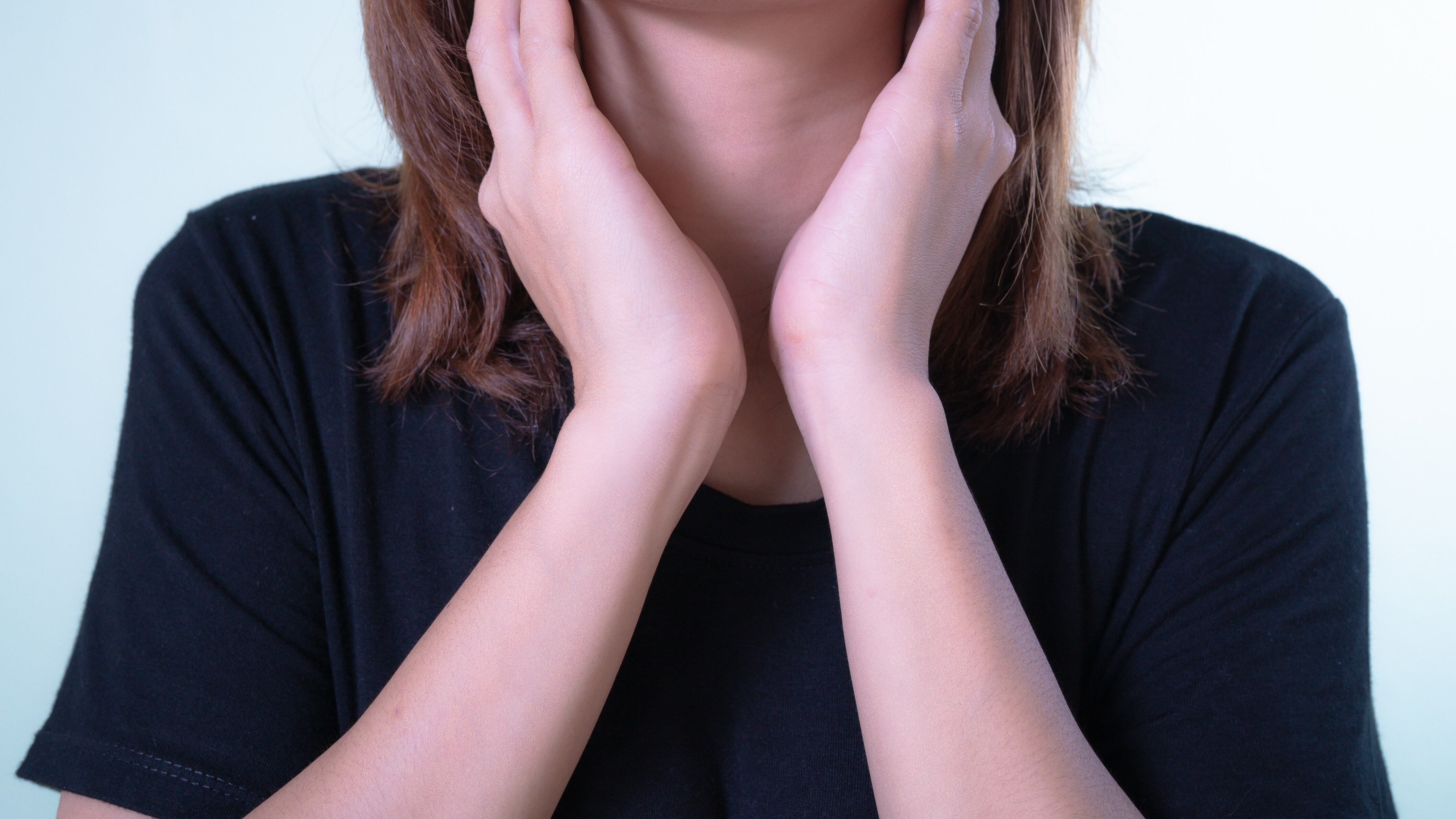 Mulher colocando as mãos no pescoço