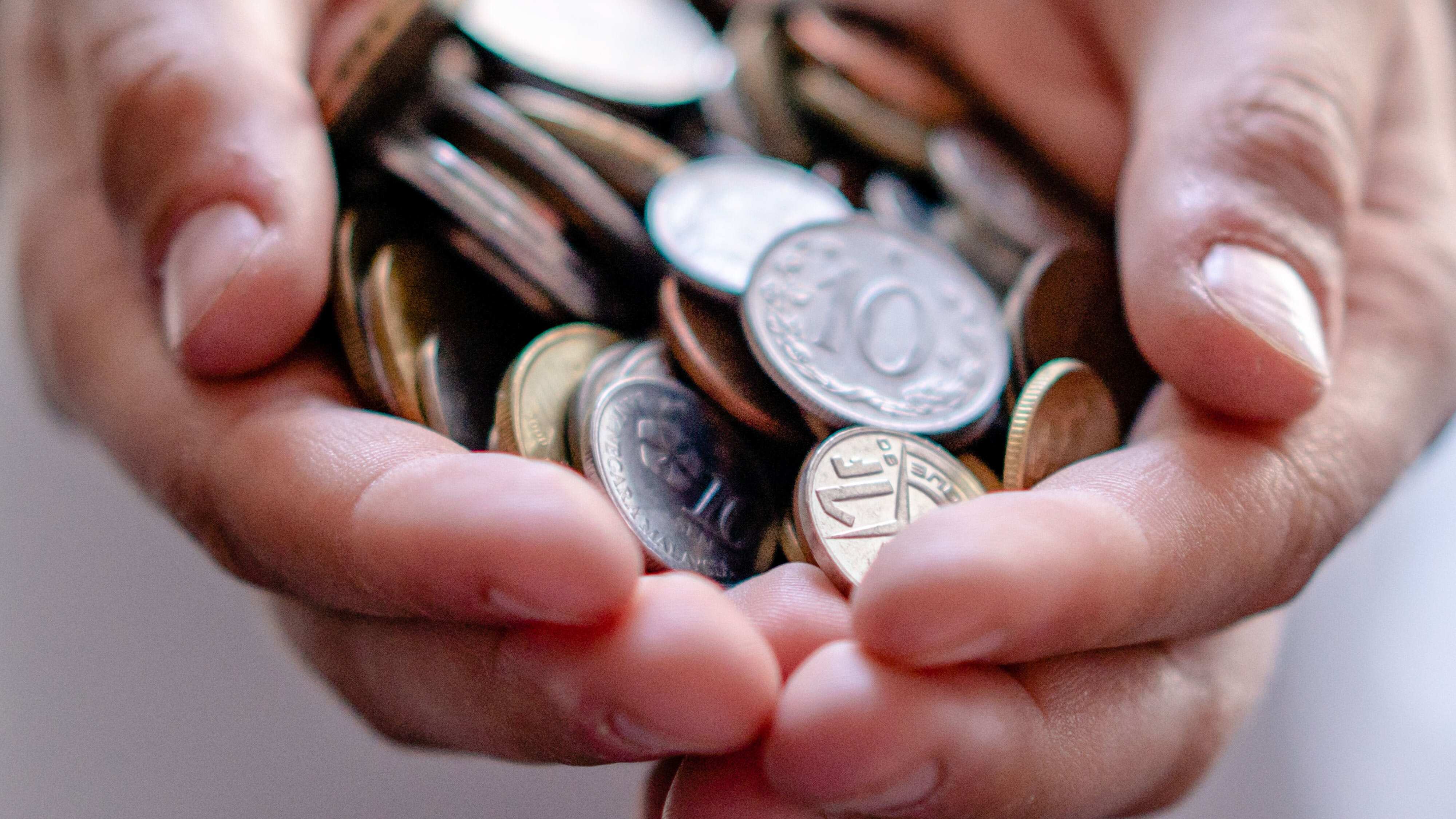 Mãos segurando diversas moedas