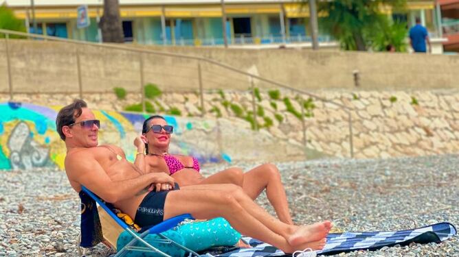 Ao lado do marido, Gretchen na praia em Menton, na França