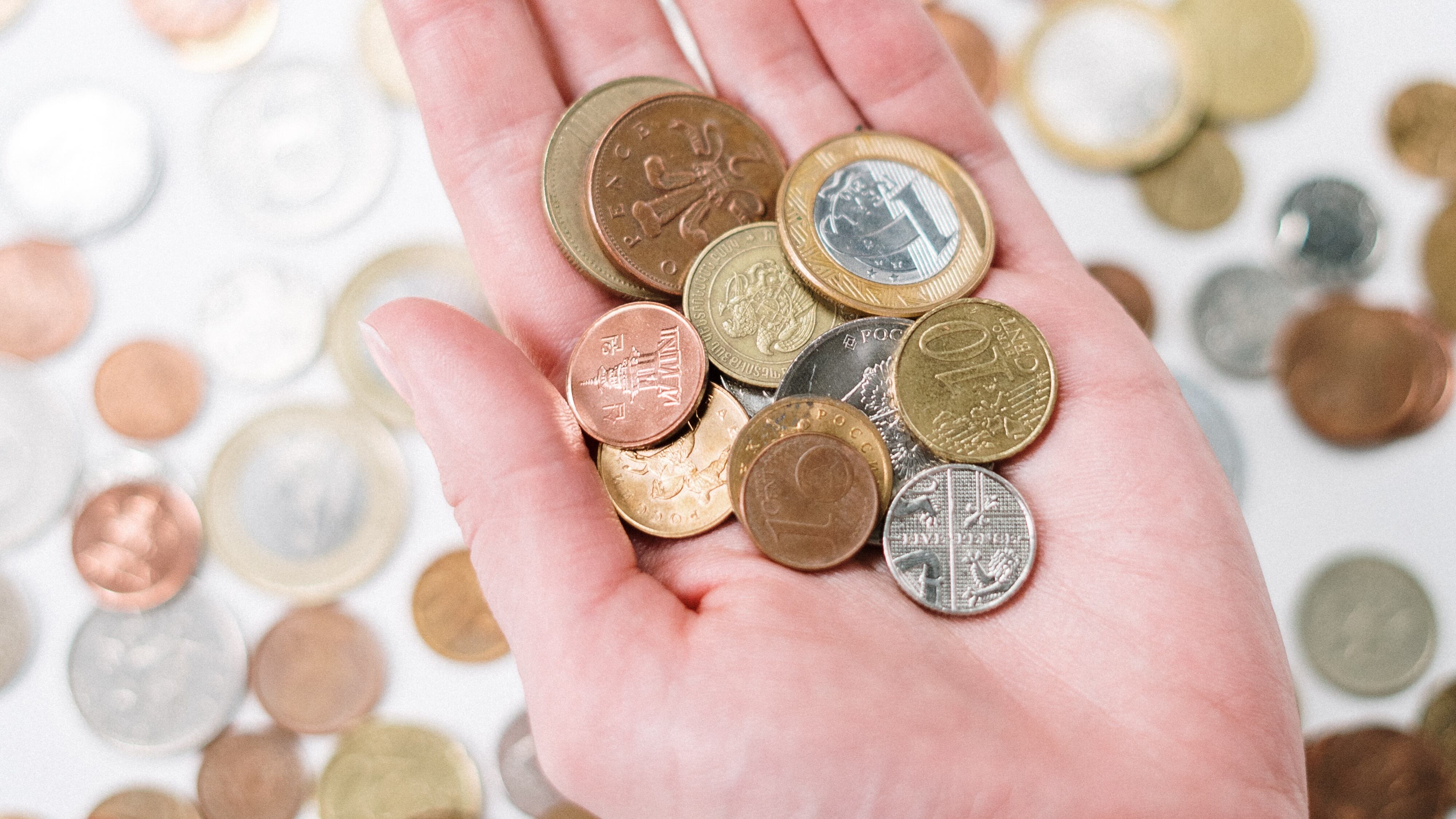 Mão masculina branca segurando moedas