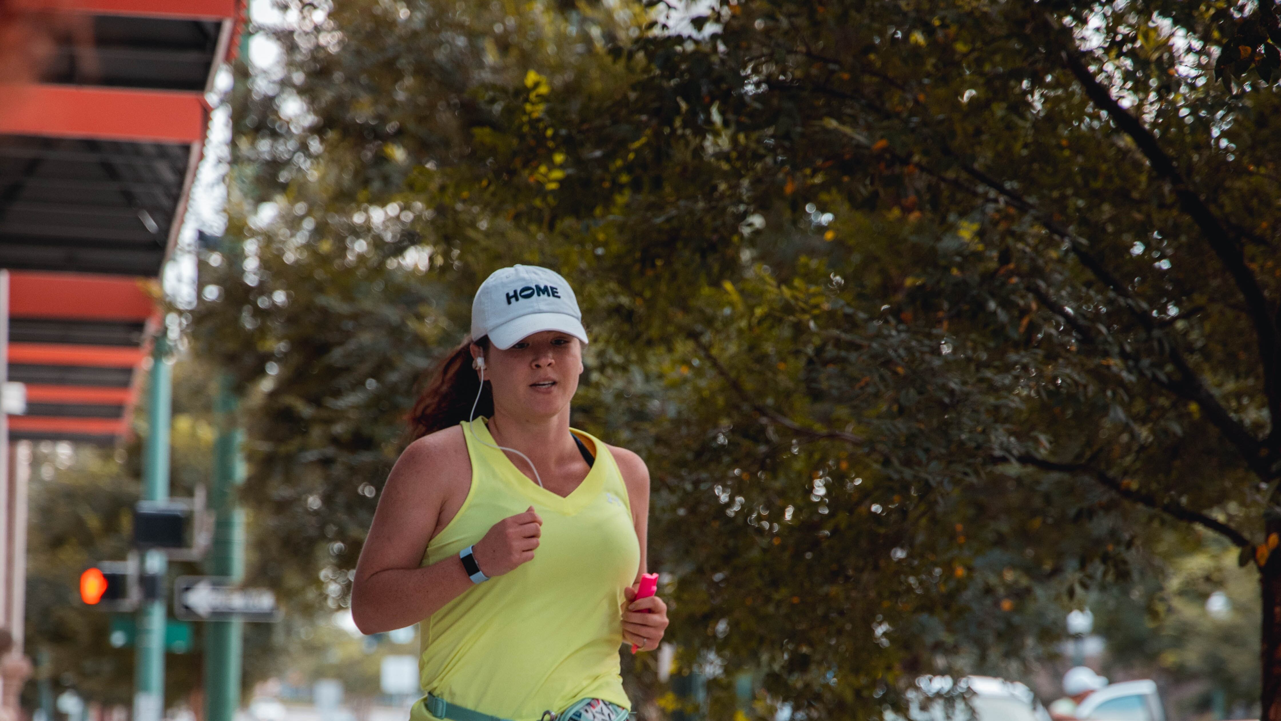 Mulher com regata amarelo correndo e levando cachorro