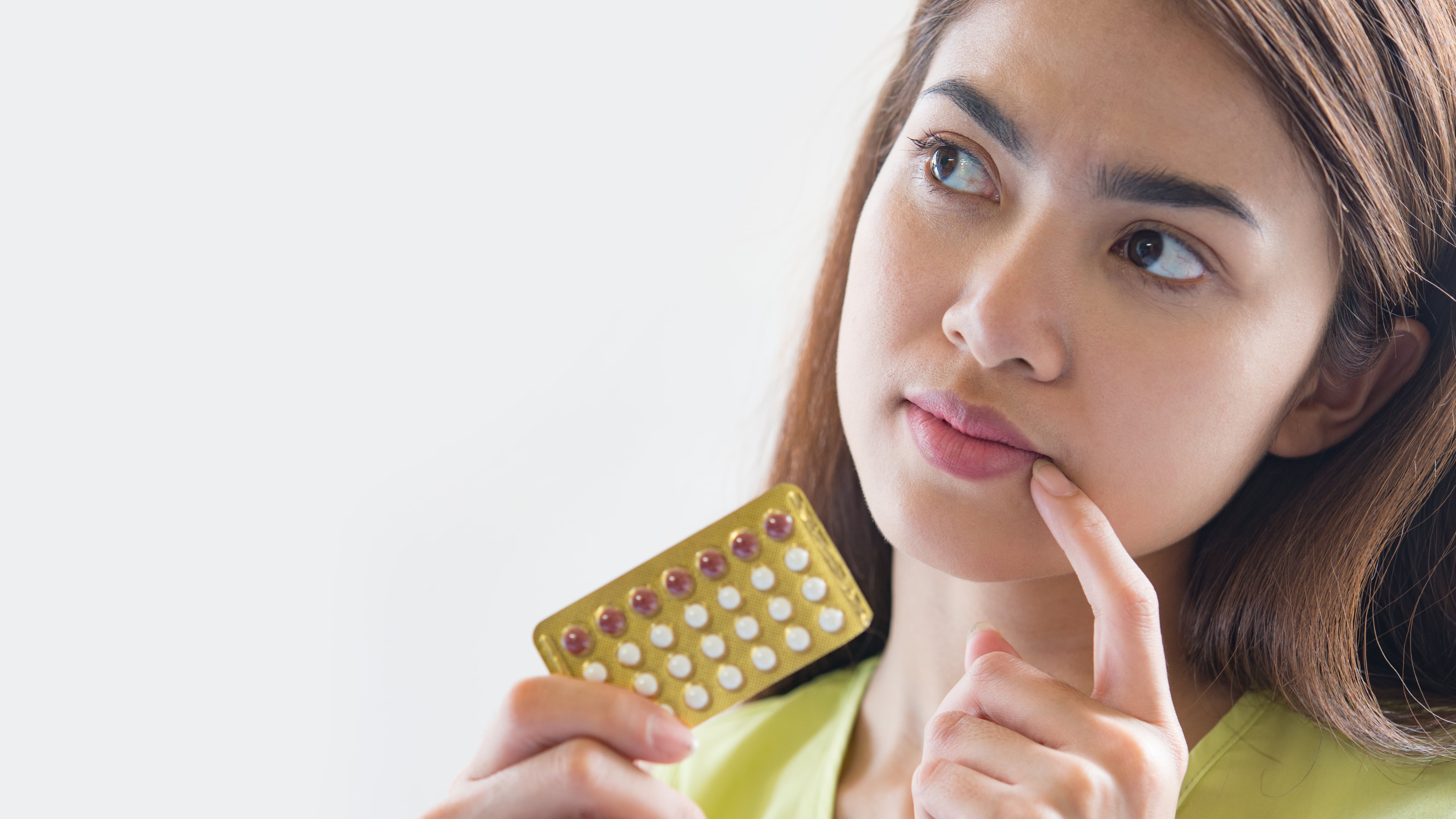 Mulher segurando cartela de pílula anticoncepcional