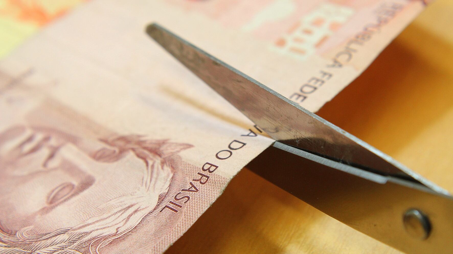 Cédula de 10 reais sendo cortada