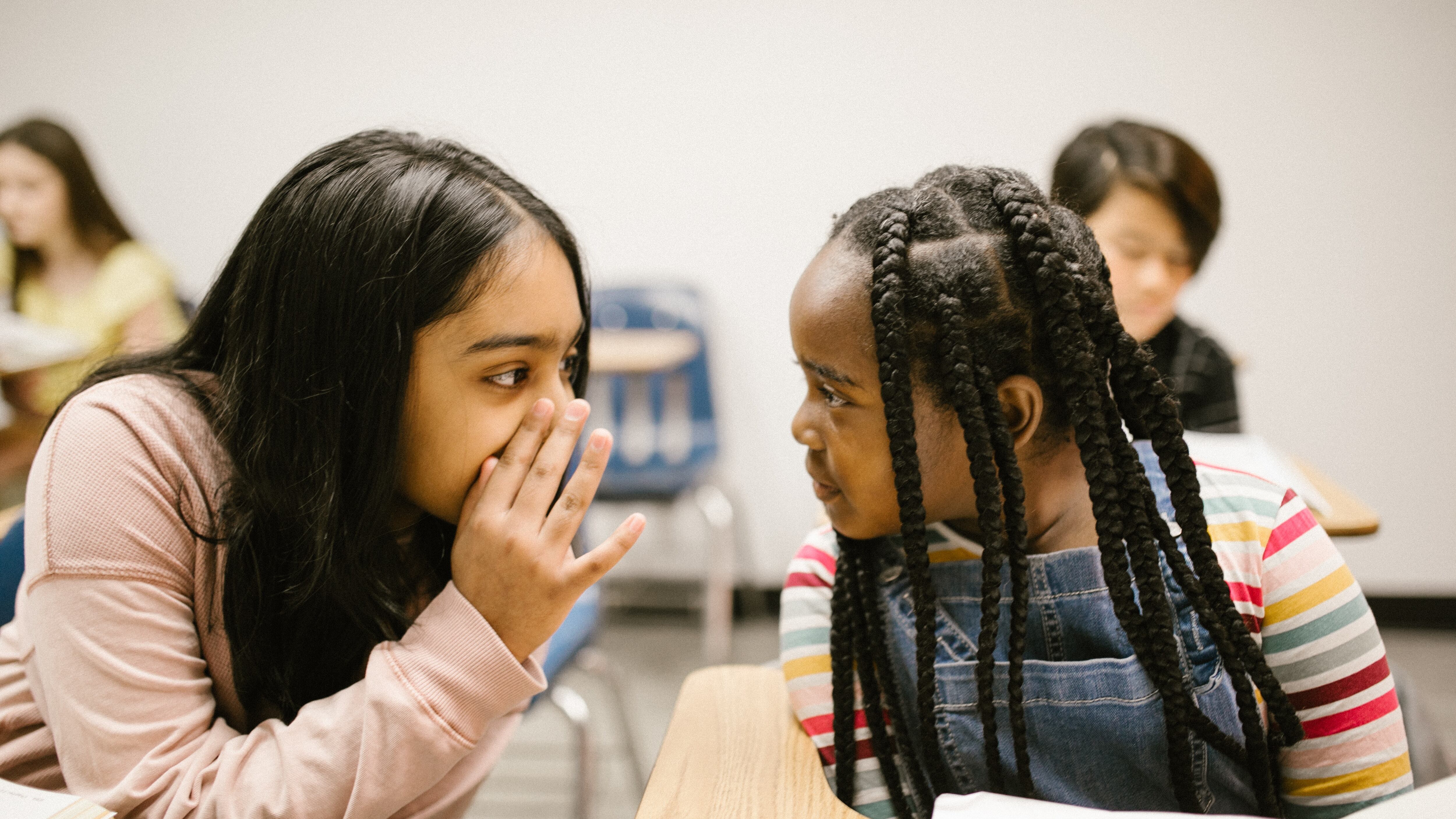 Duas meninas adolescentes fofocando na sala de aula