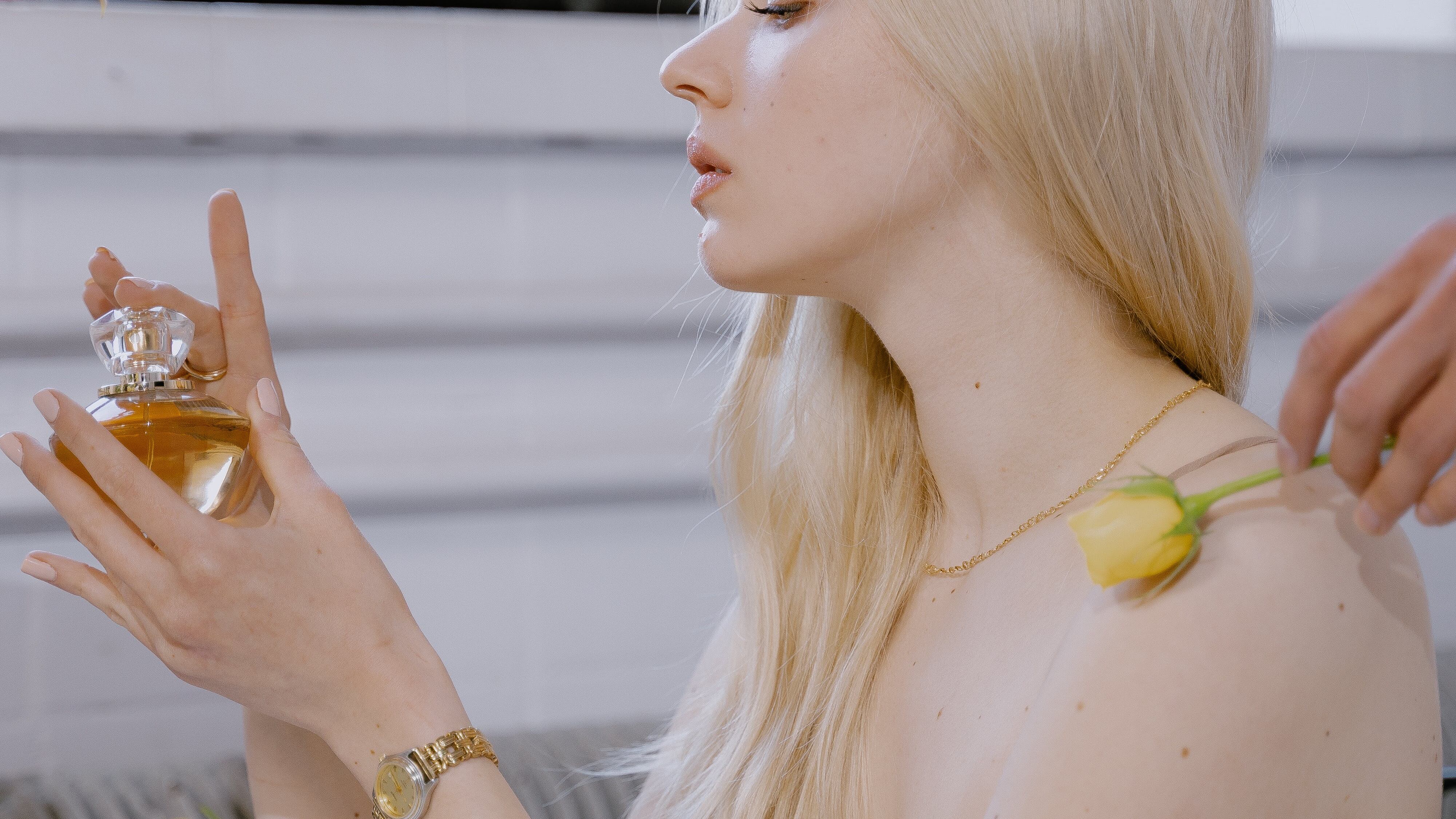 Mulher loira segurando frasco de perfume