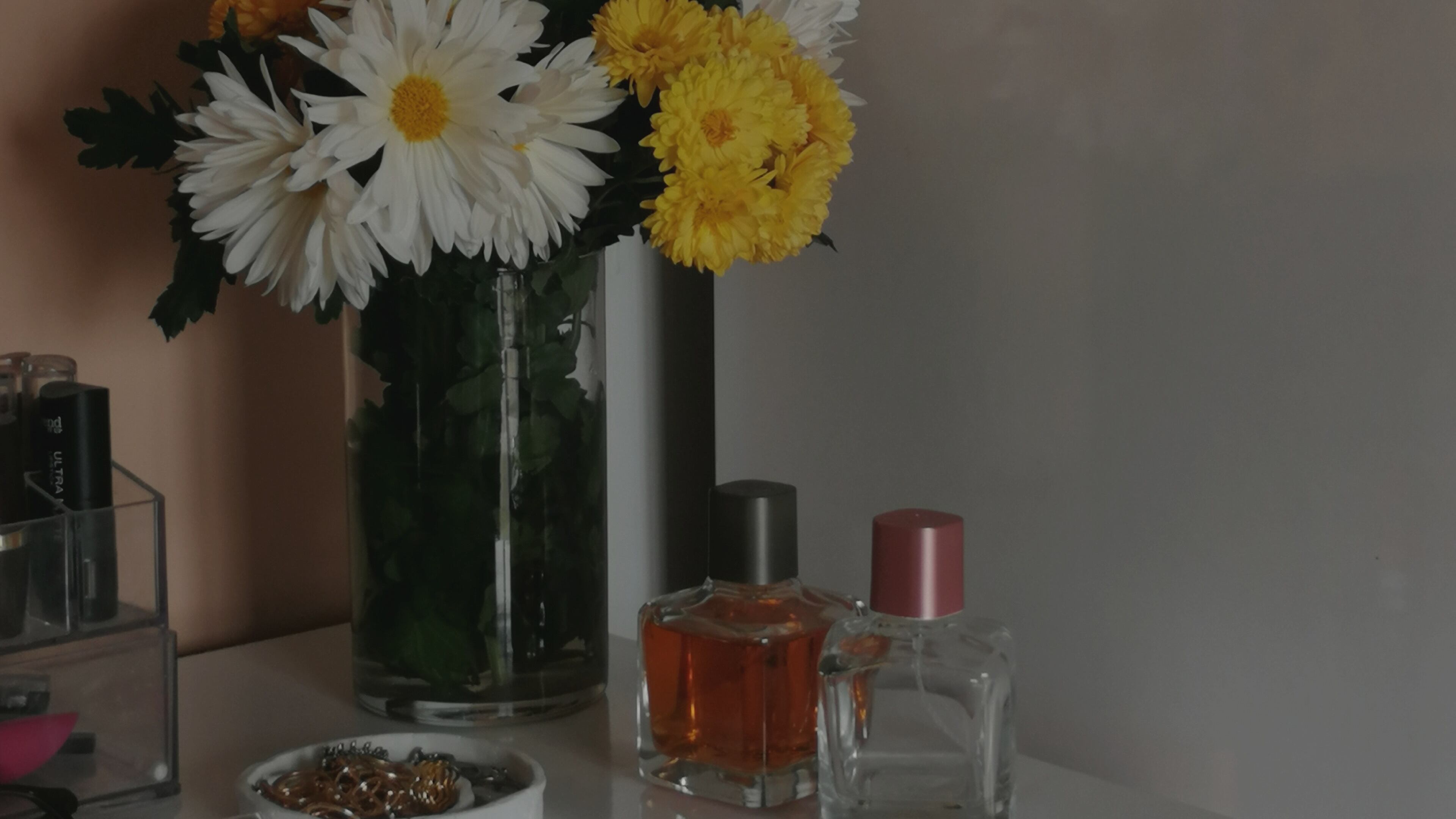 Frascos de perfume ao lado de vaso de flores