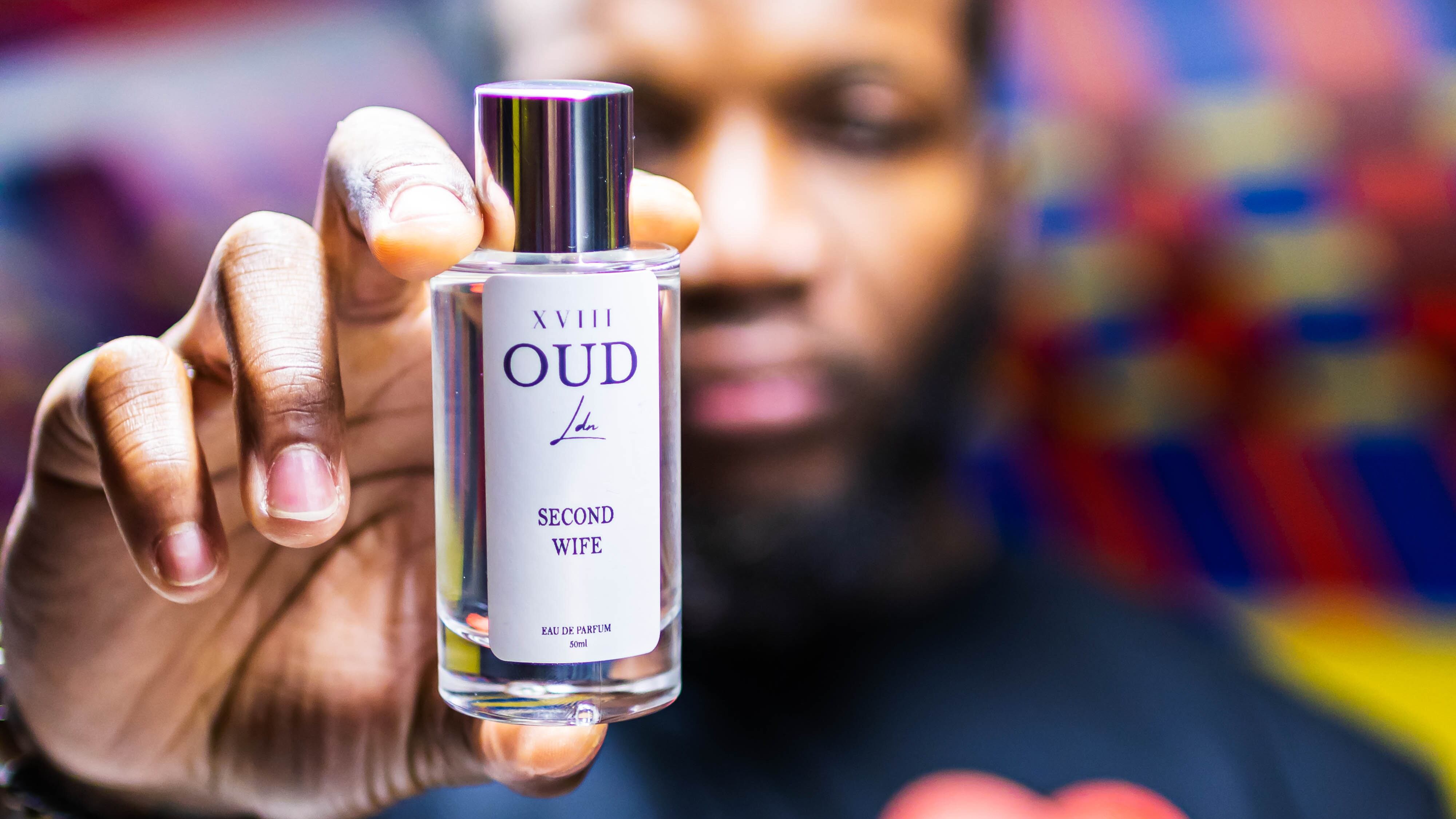 Homem negro mostrando frasco de perfume