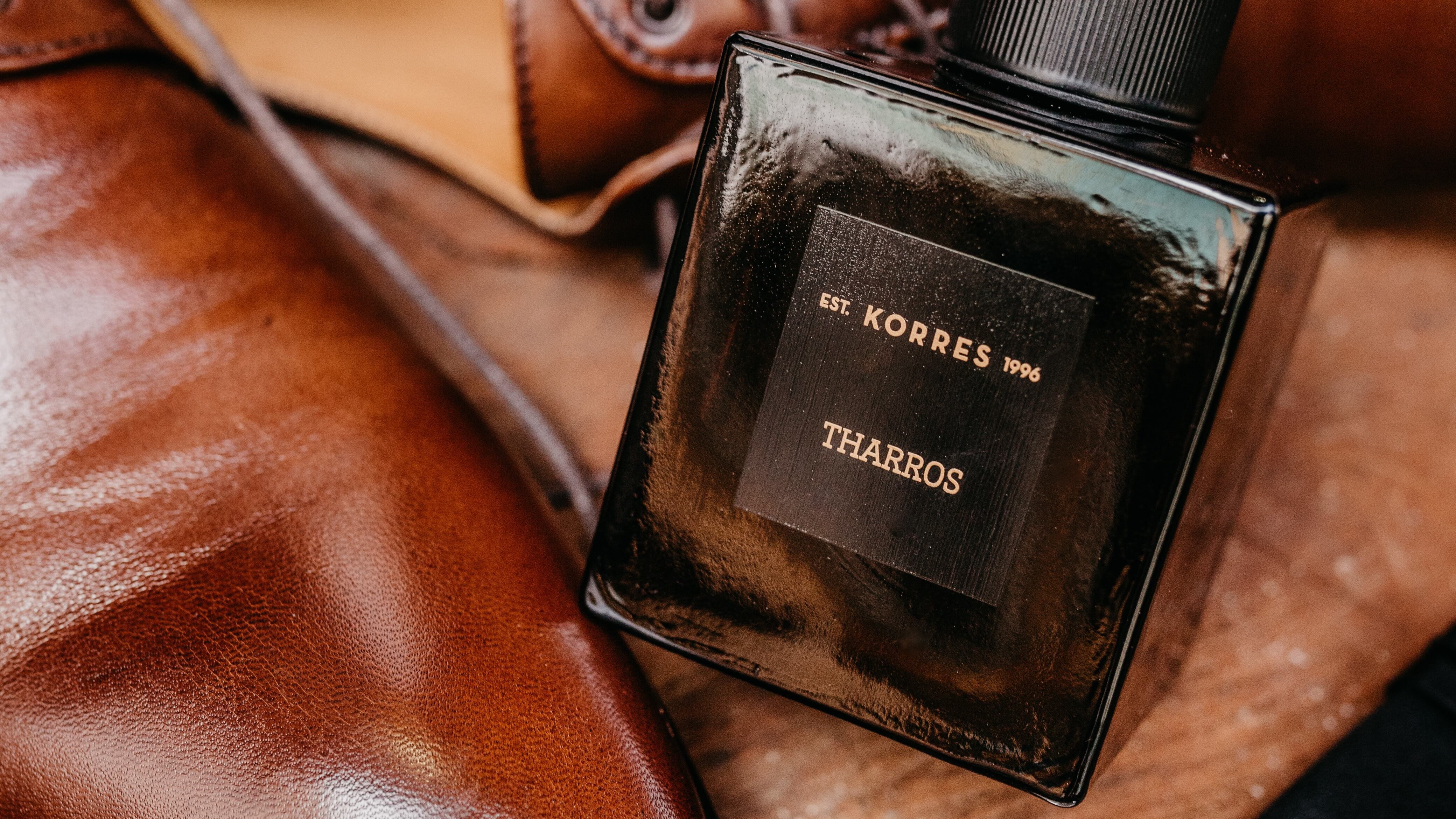 Frasco de perfume ao lado de sapato social marrom e relógio