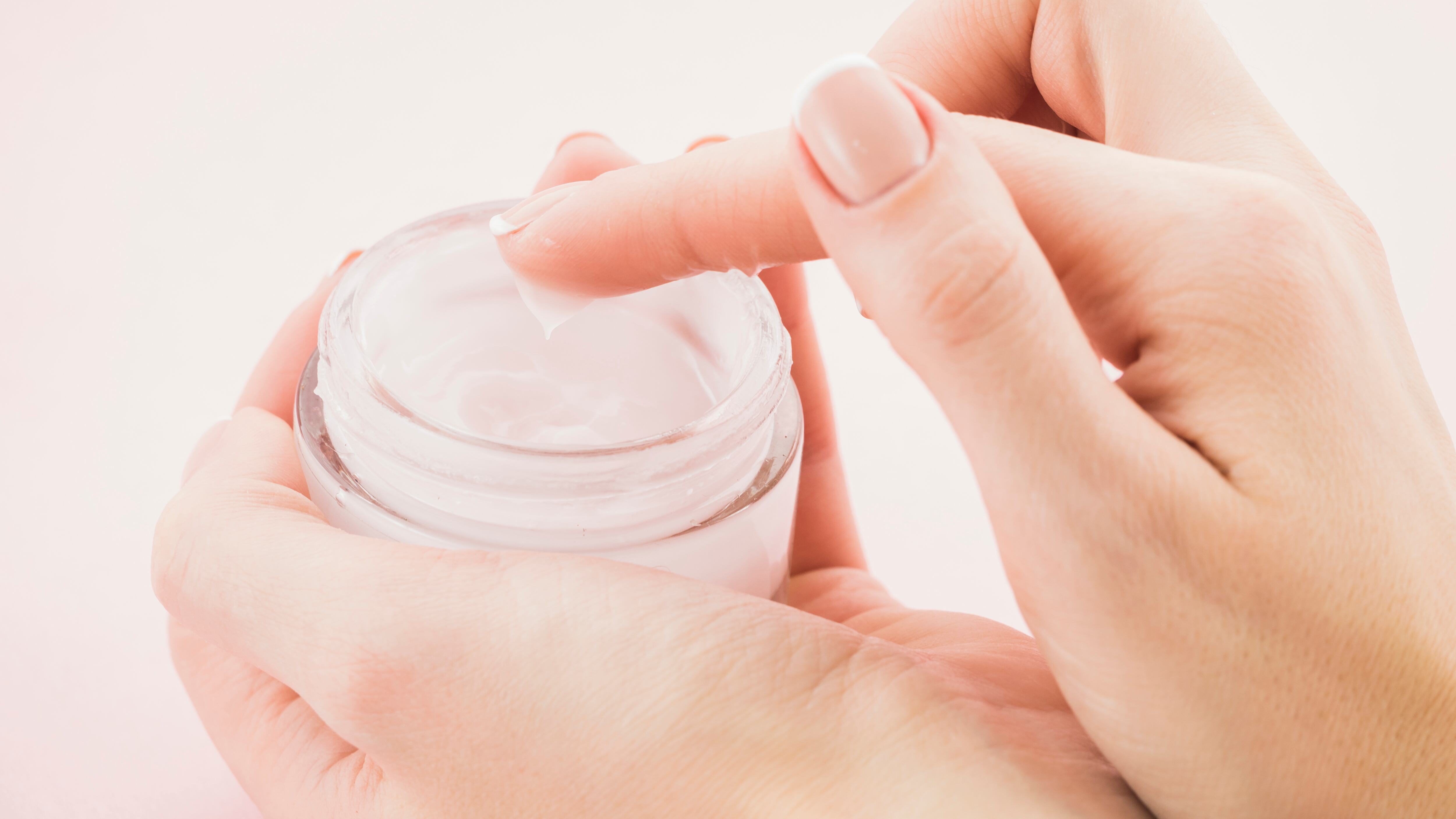 Silhueta de mão feminina segurando pote de hidratante