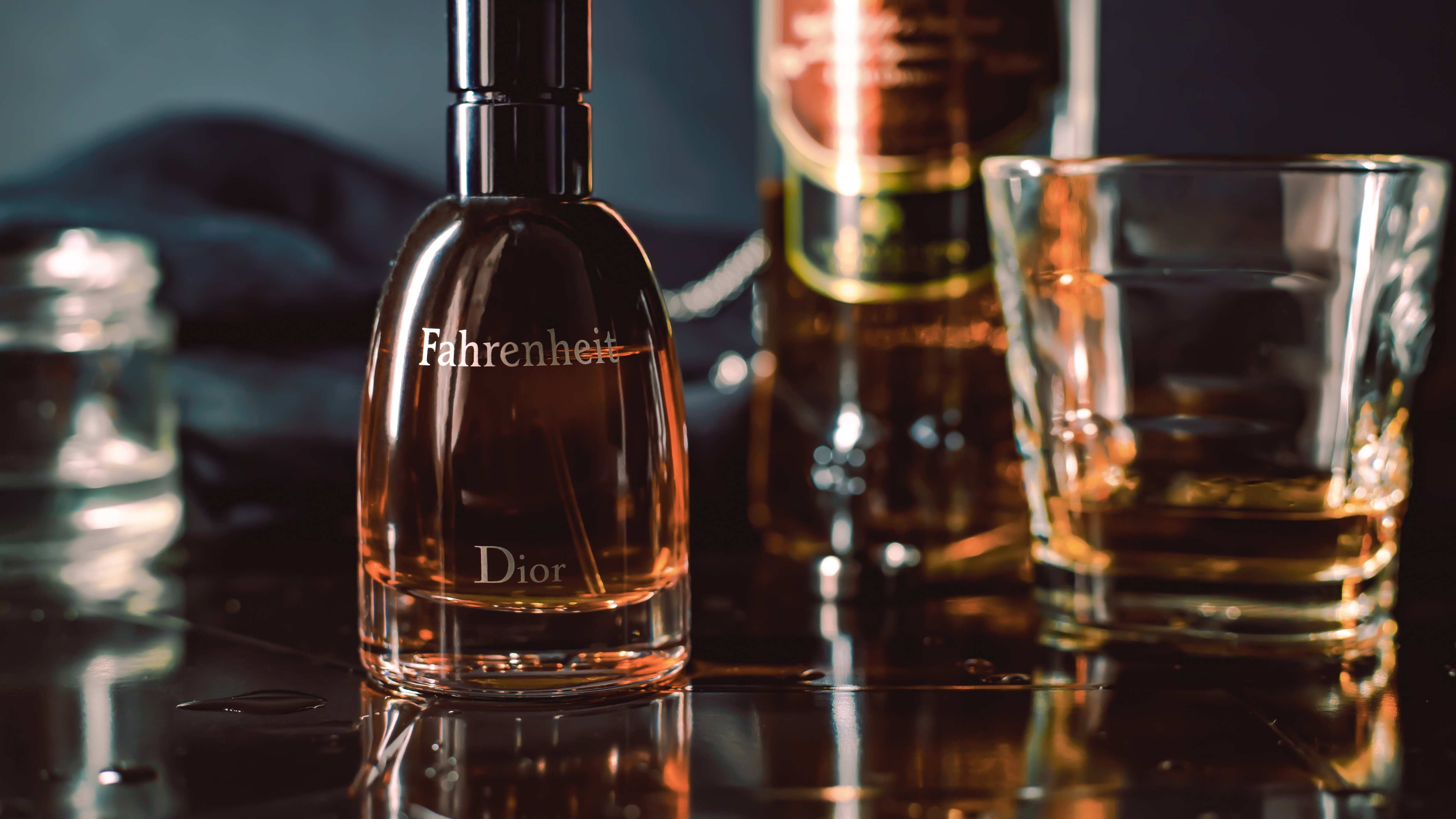 Frasco de perfume da Dior ao lado de copo de whisky