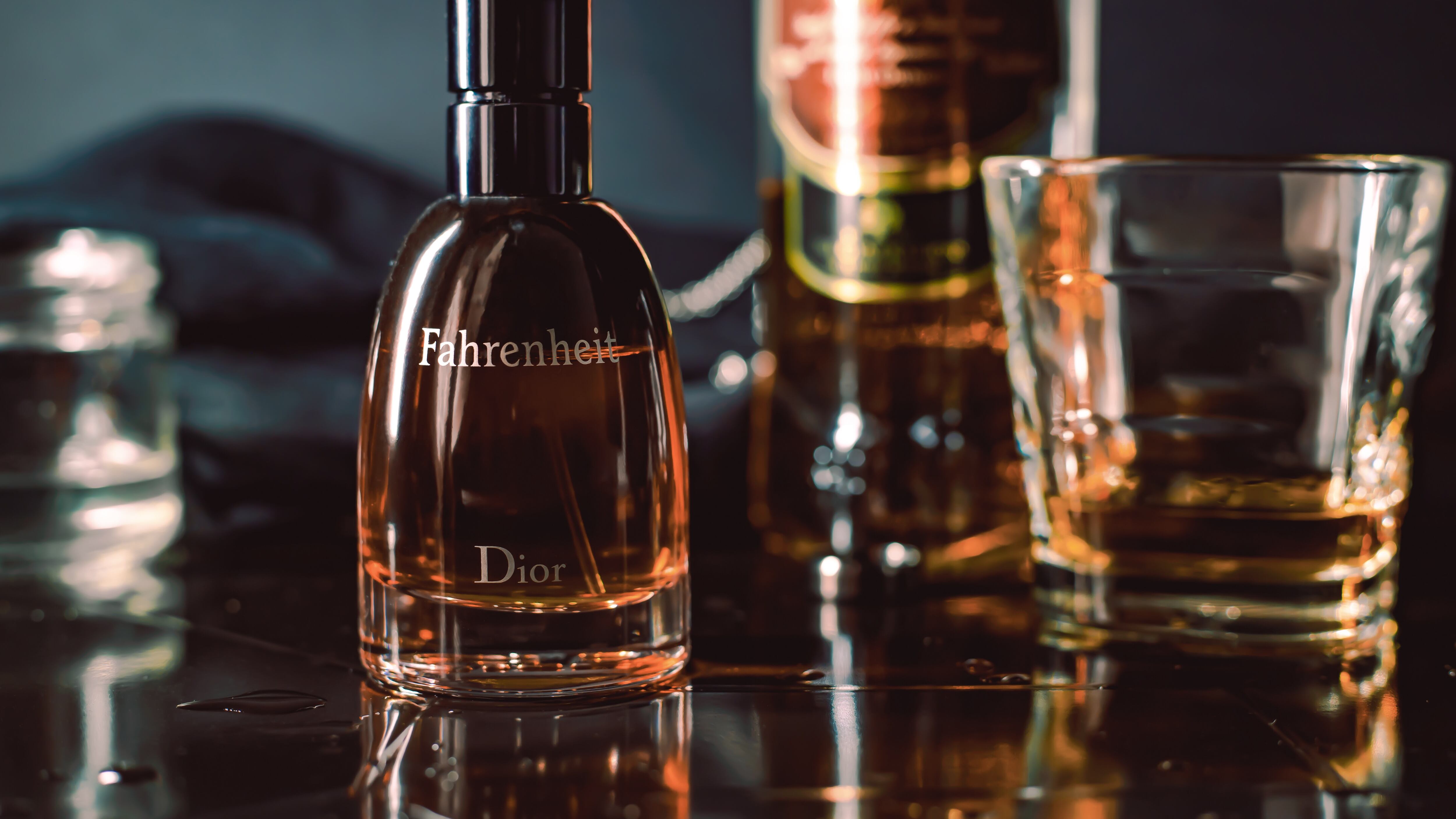 Frasco de perfume da Dior ao lado de copo de whisky