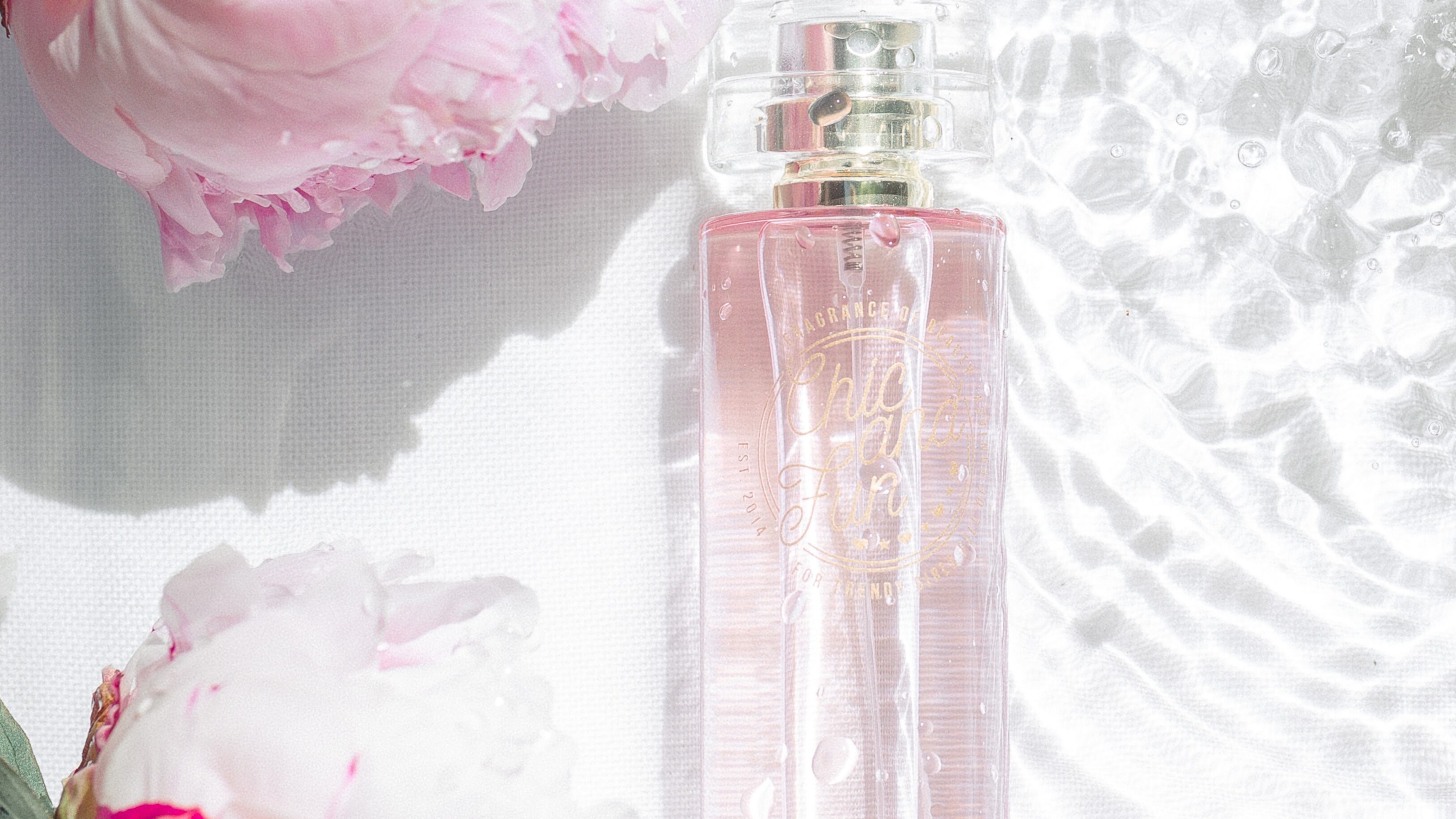 Frasco de perfume ao lado de rosas