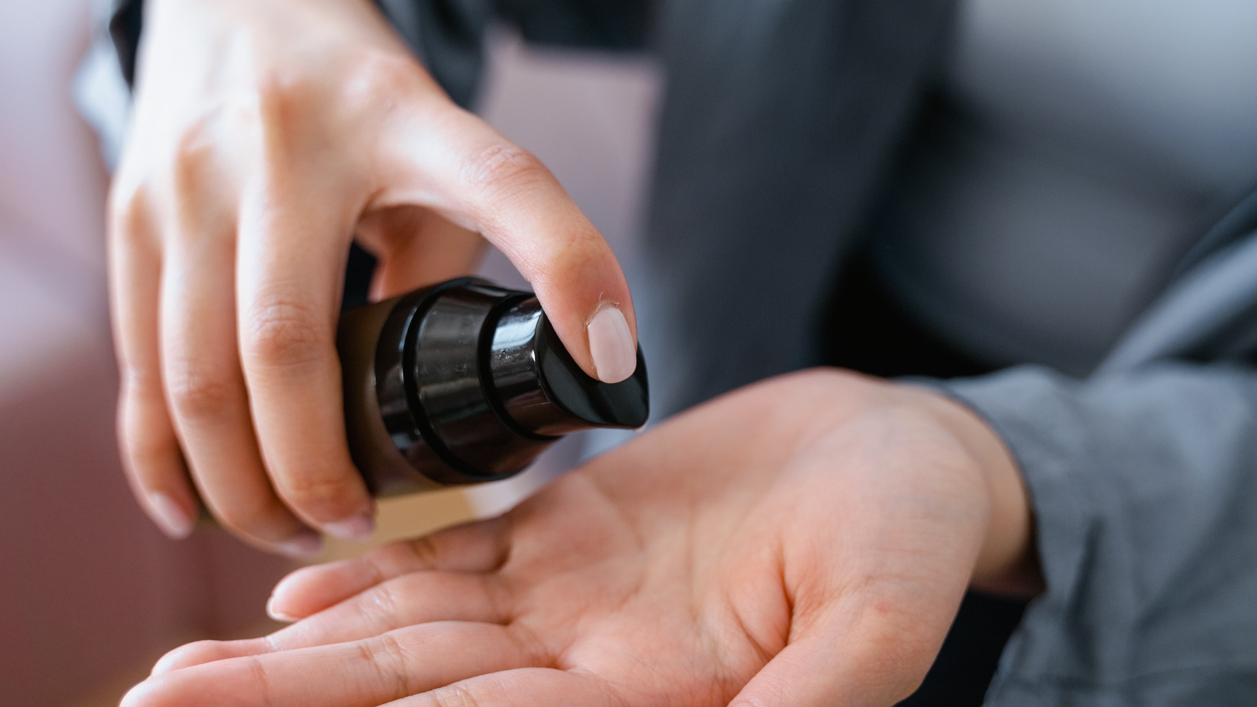 Mulher com pote de hidratante colocando produto na mão