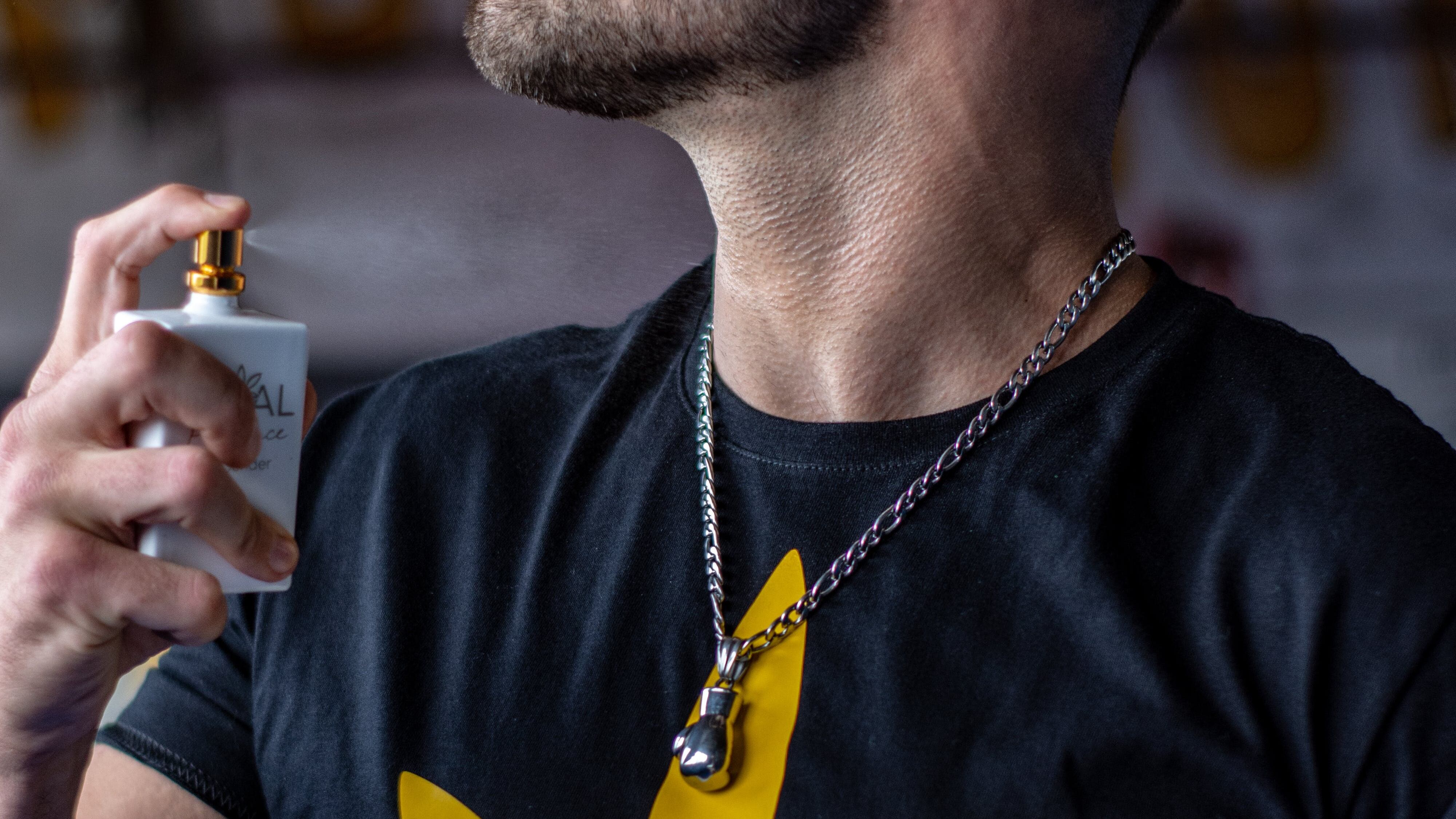 Homem borrifando perfume no pescoço