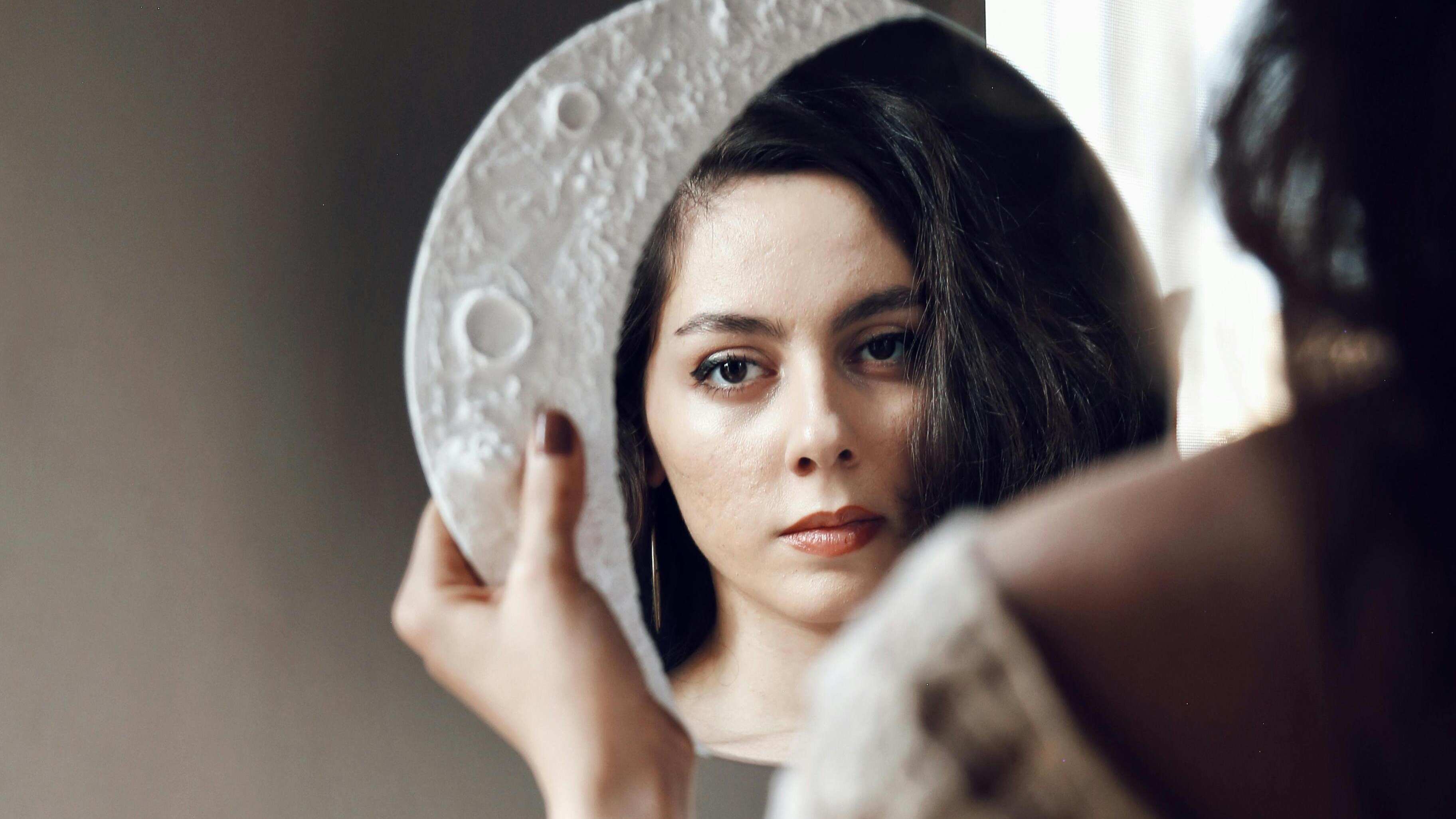 Mulher olhando para espelho de lua.