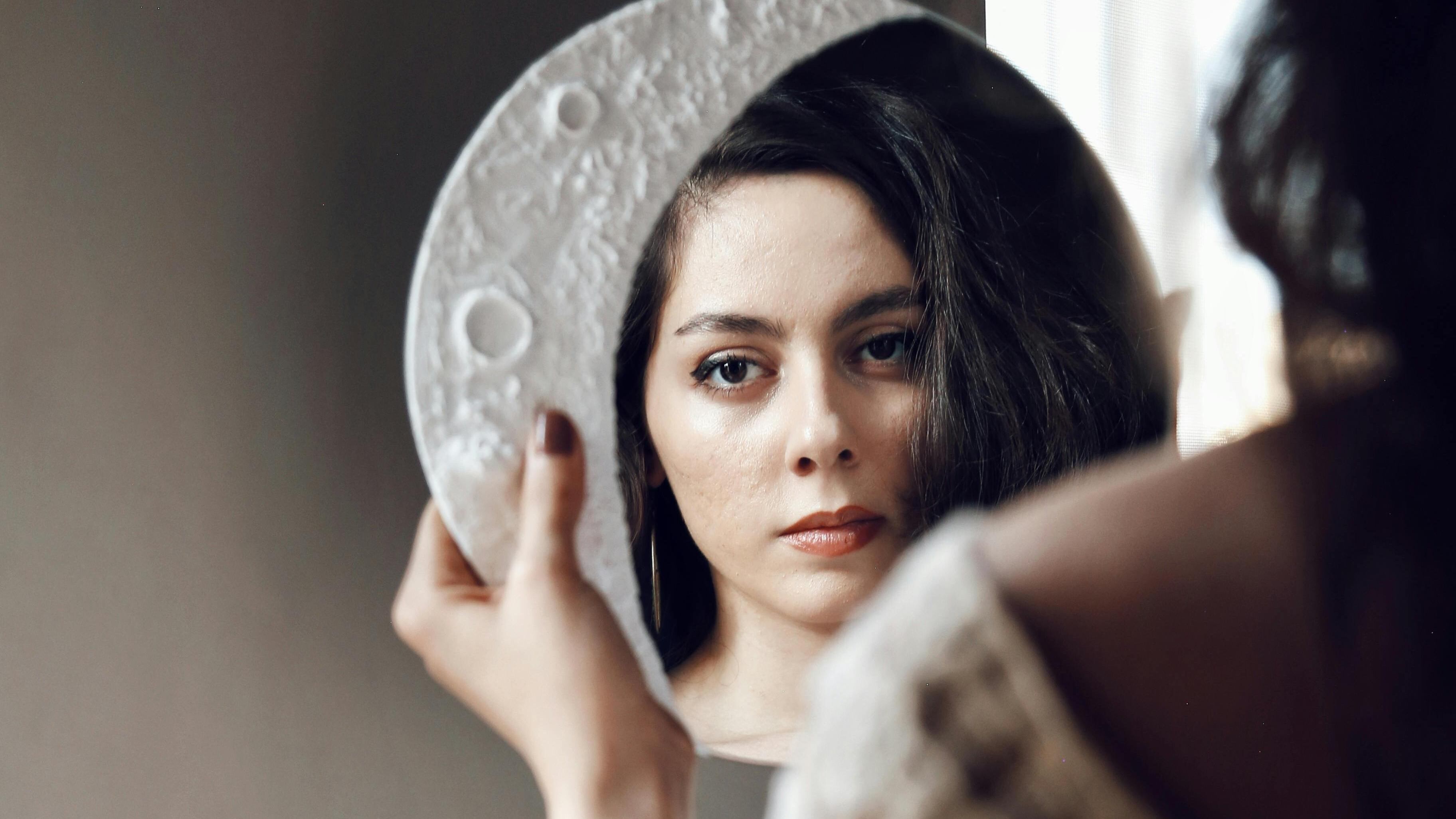Mulher olhando para espelho de lua.