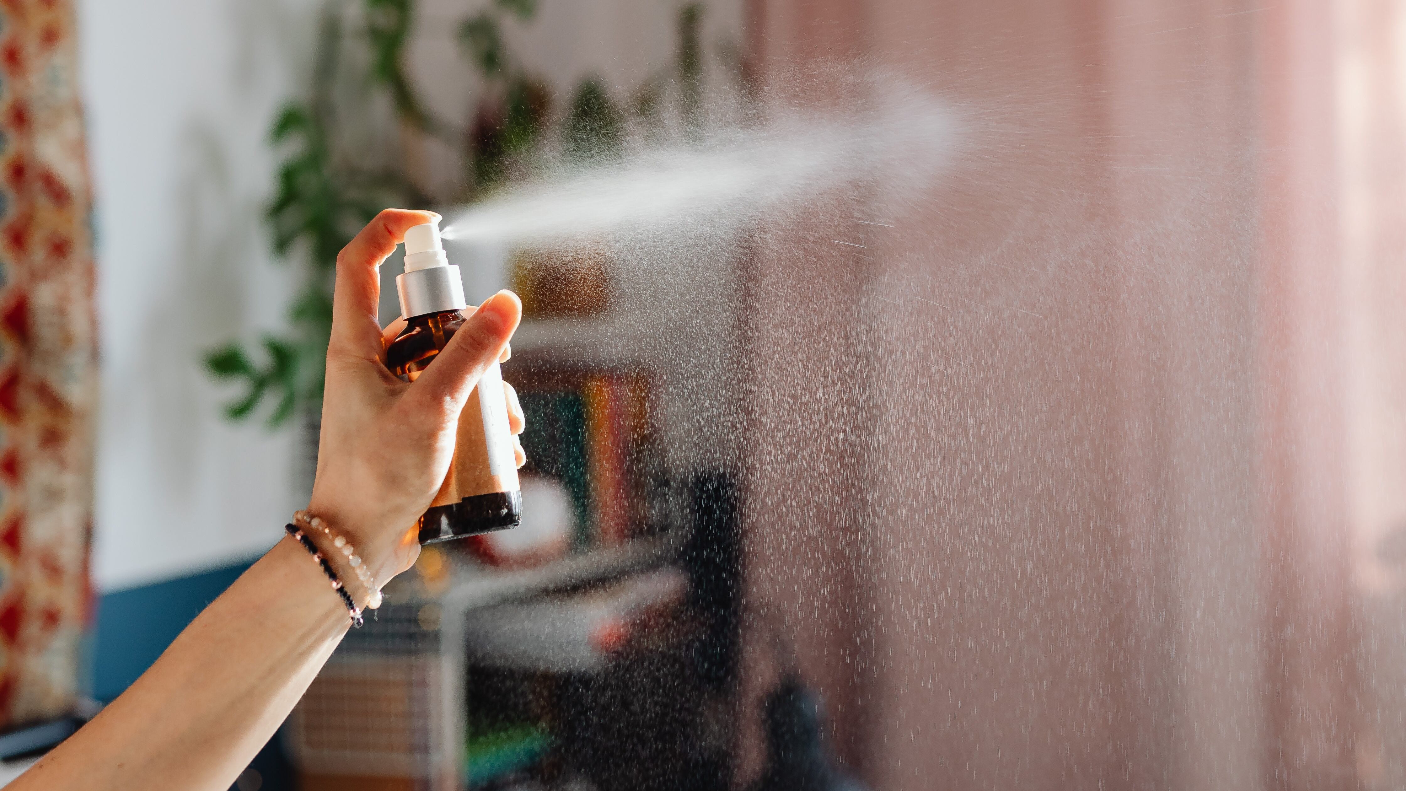 Mão femininas borrifando home spray