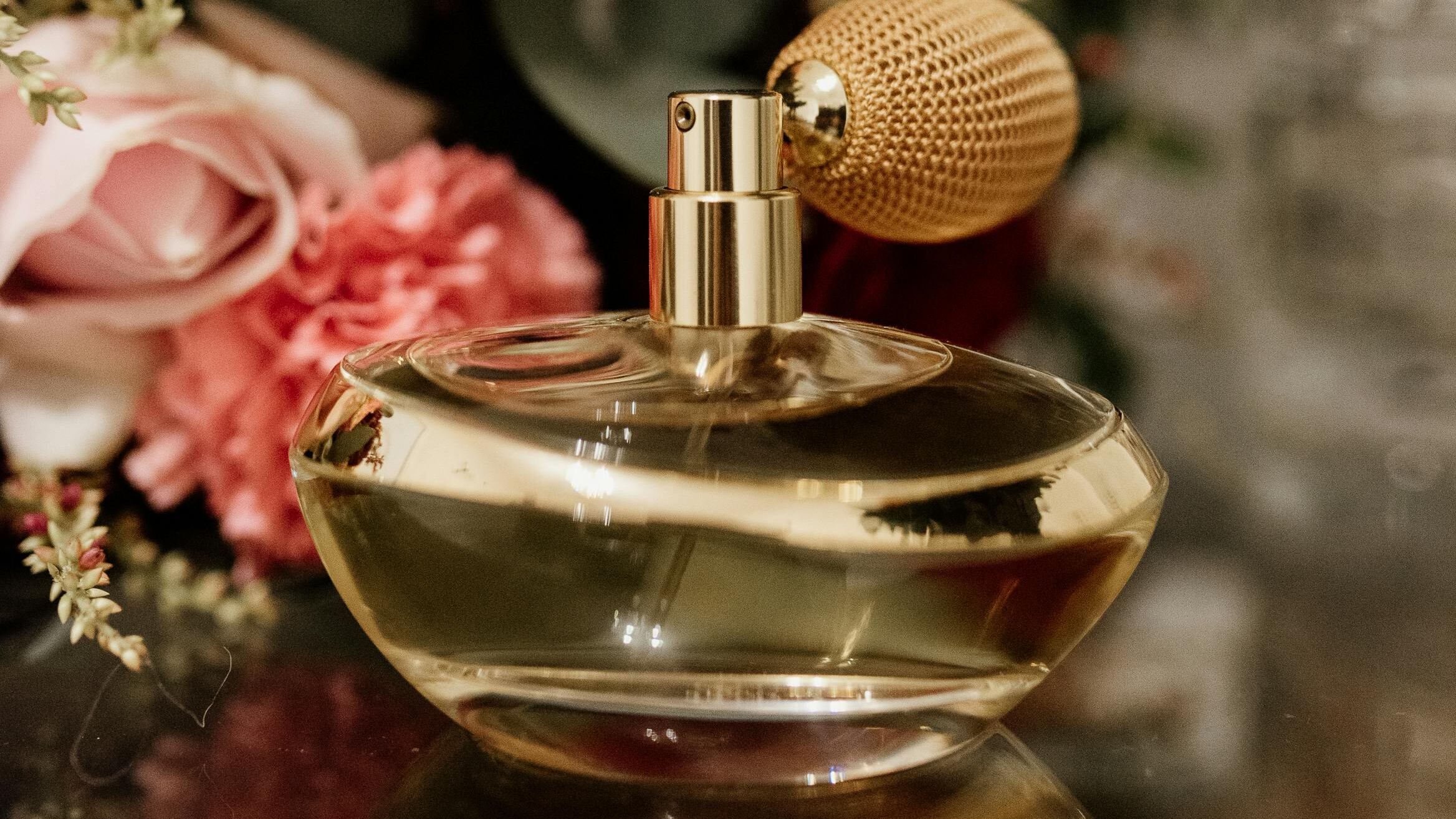 Frasco de perfume com rosas ao fundo