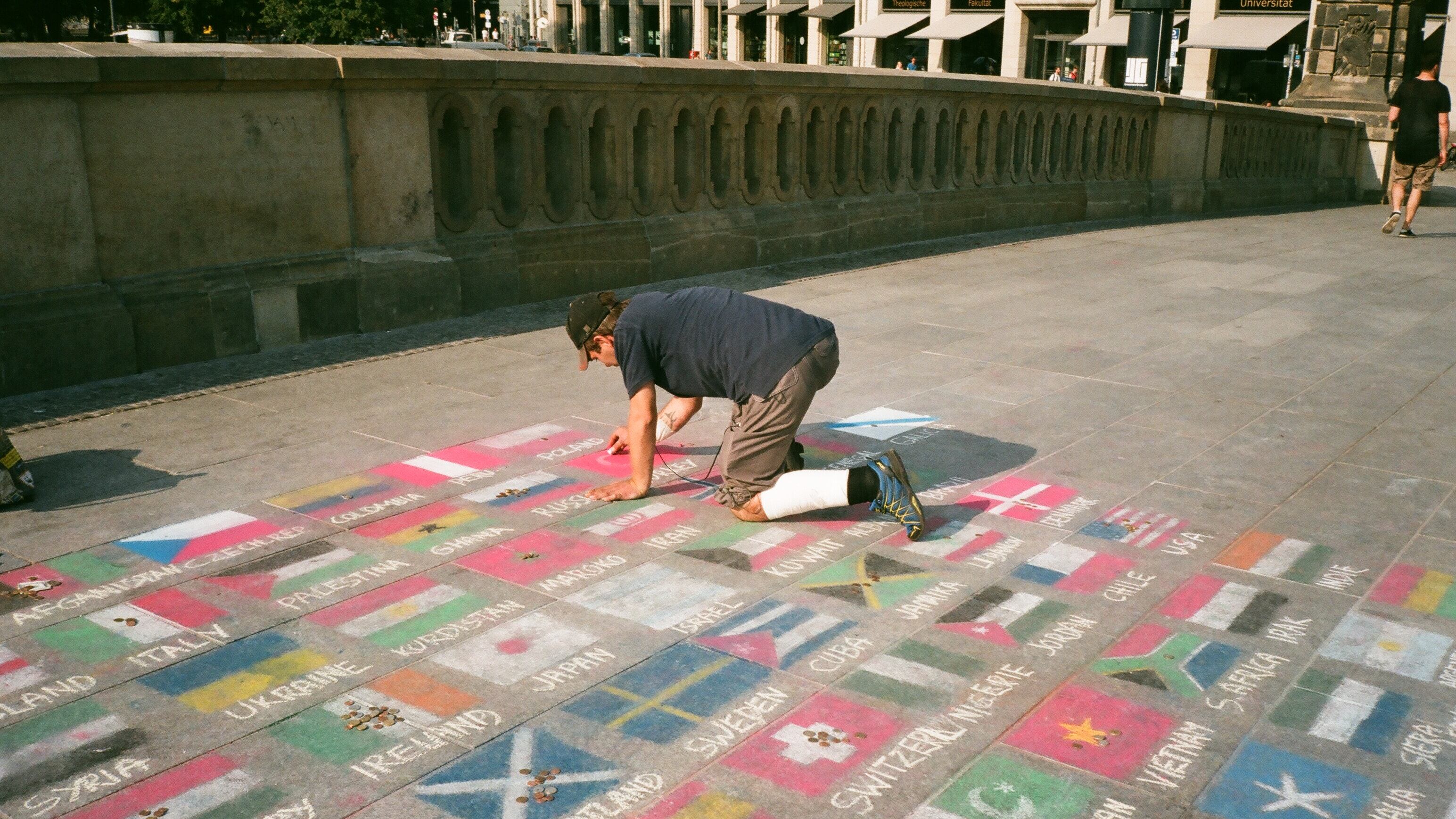 Homem desenhando bandeiras dos países no chão
