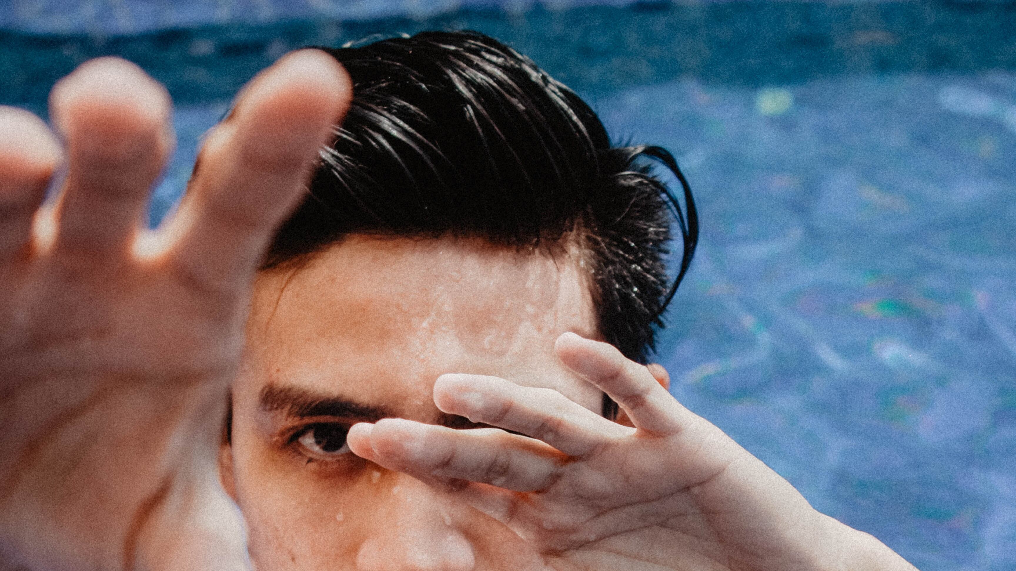 Homem dentro da piscina mostrando as mãos