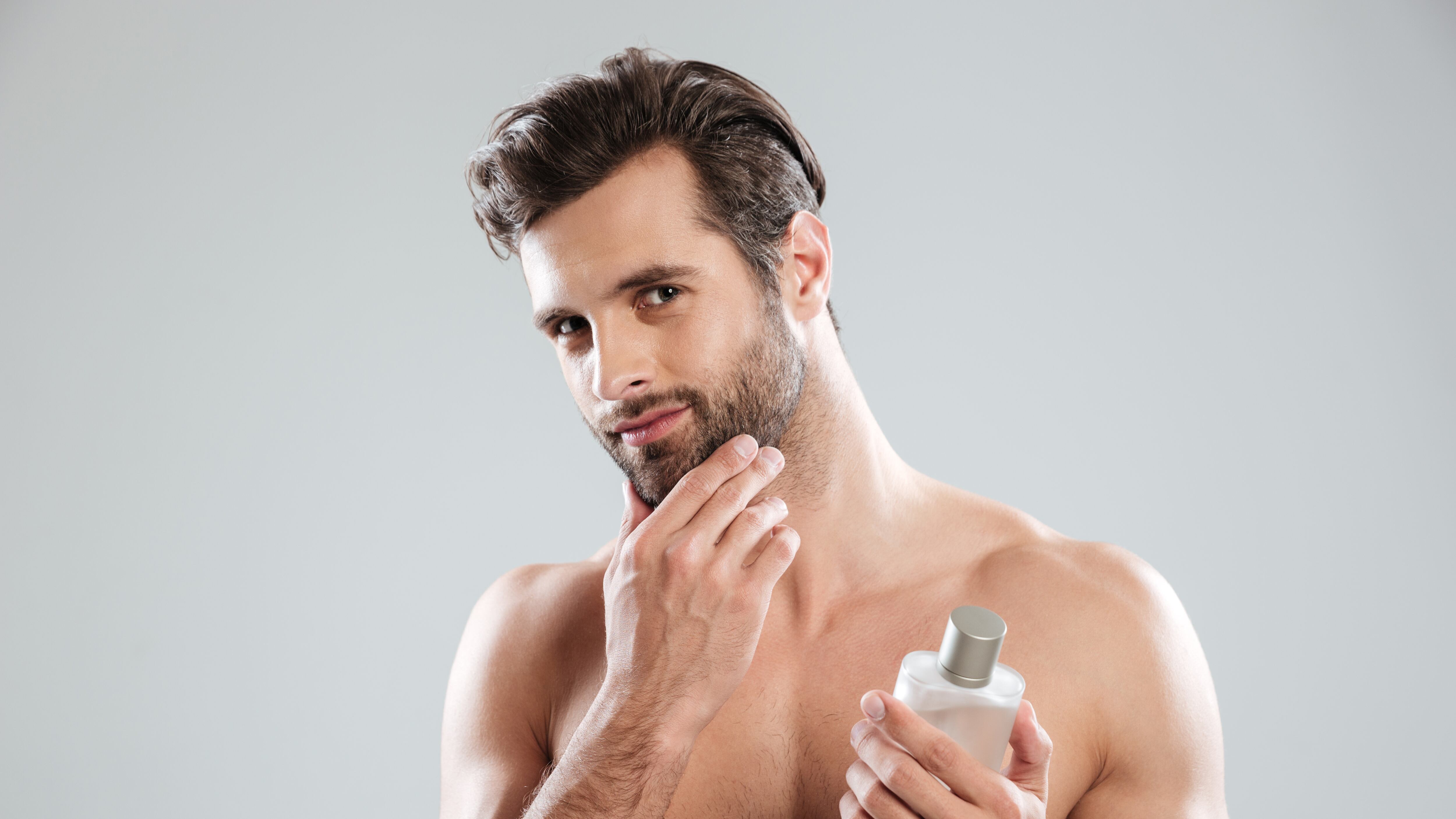 Homem sem camisa segurando perfume