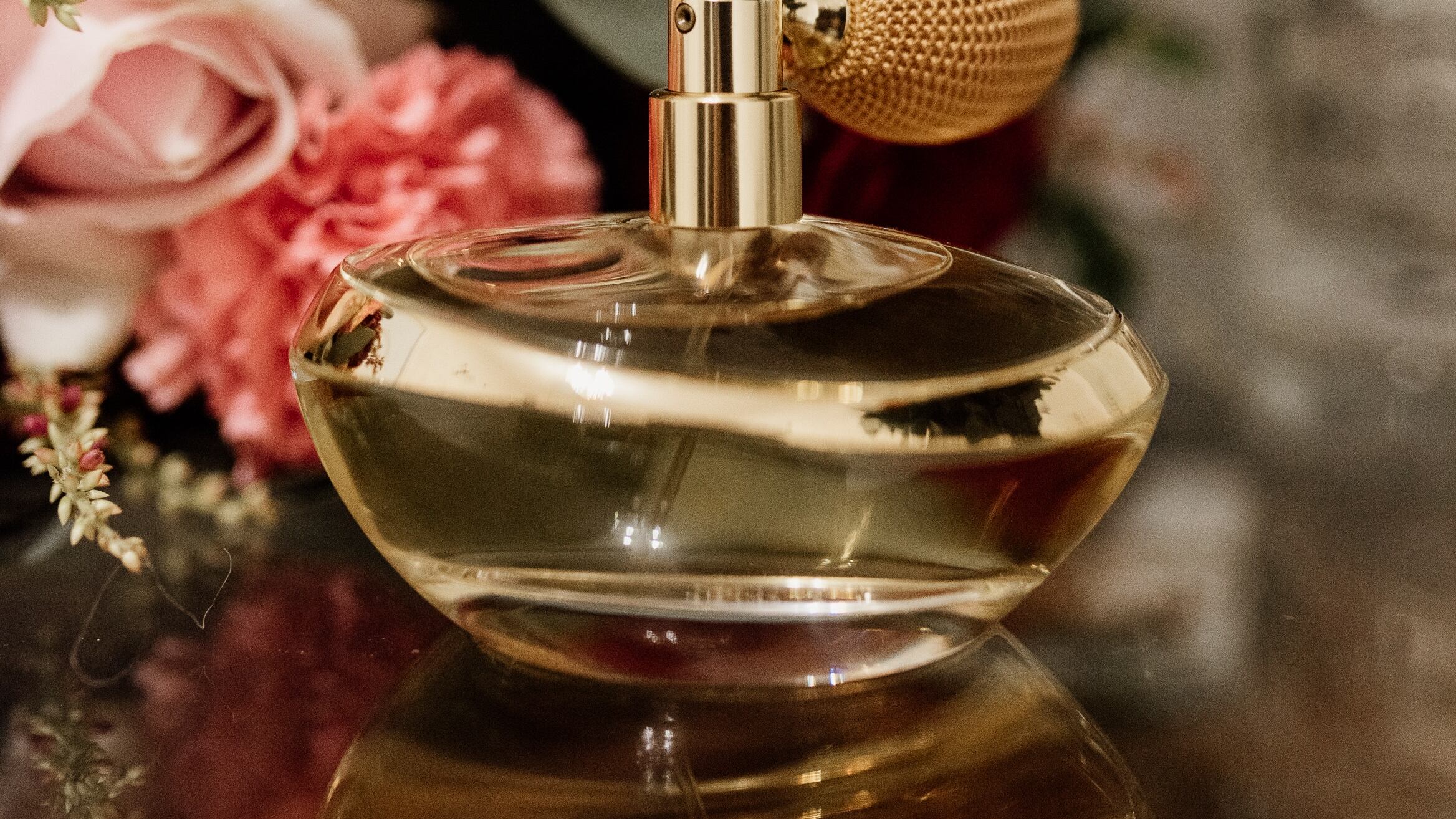 Frasco de perfume vintage ao lado de buquê de rosas