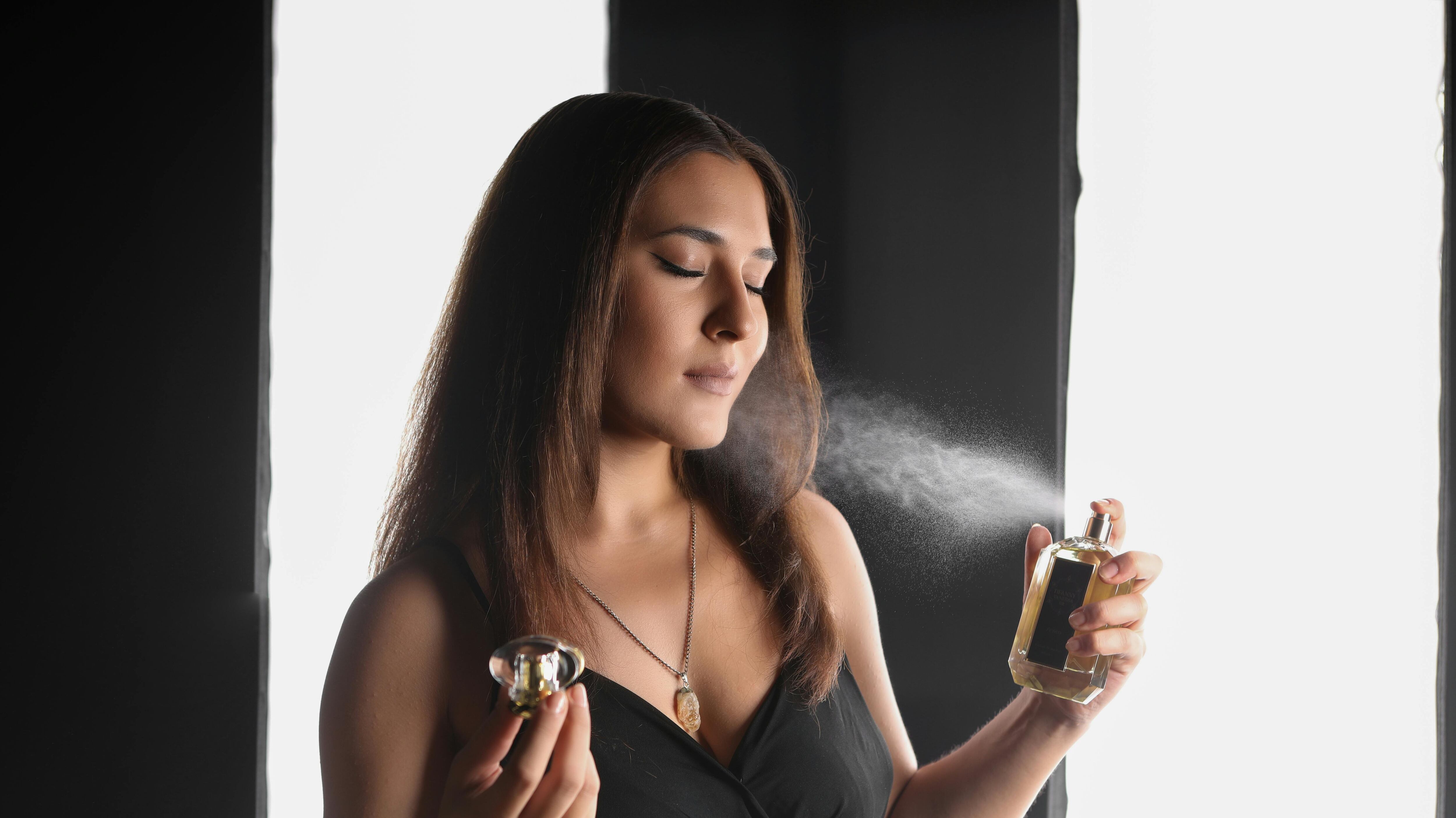 Mulher espirrando frasco de perfume no pescoço