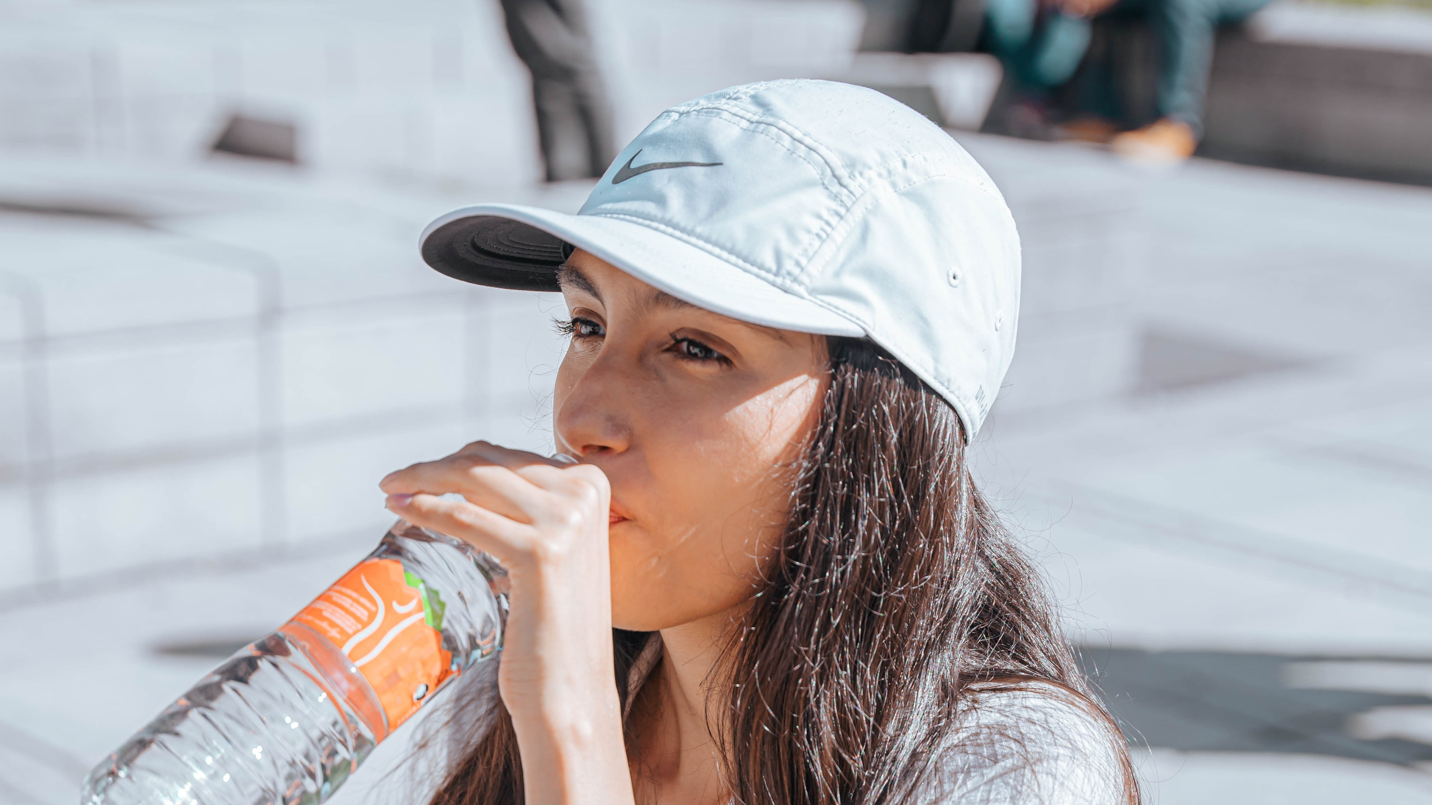 Mulher de boné tomando sol e bebendo água