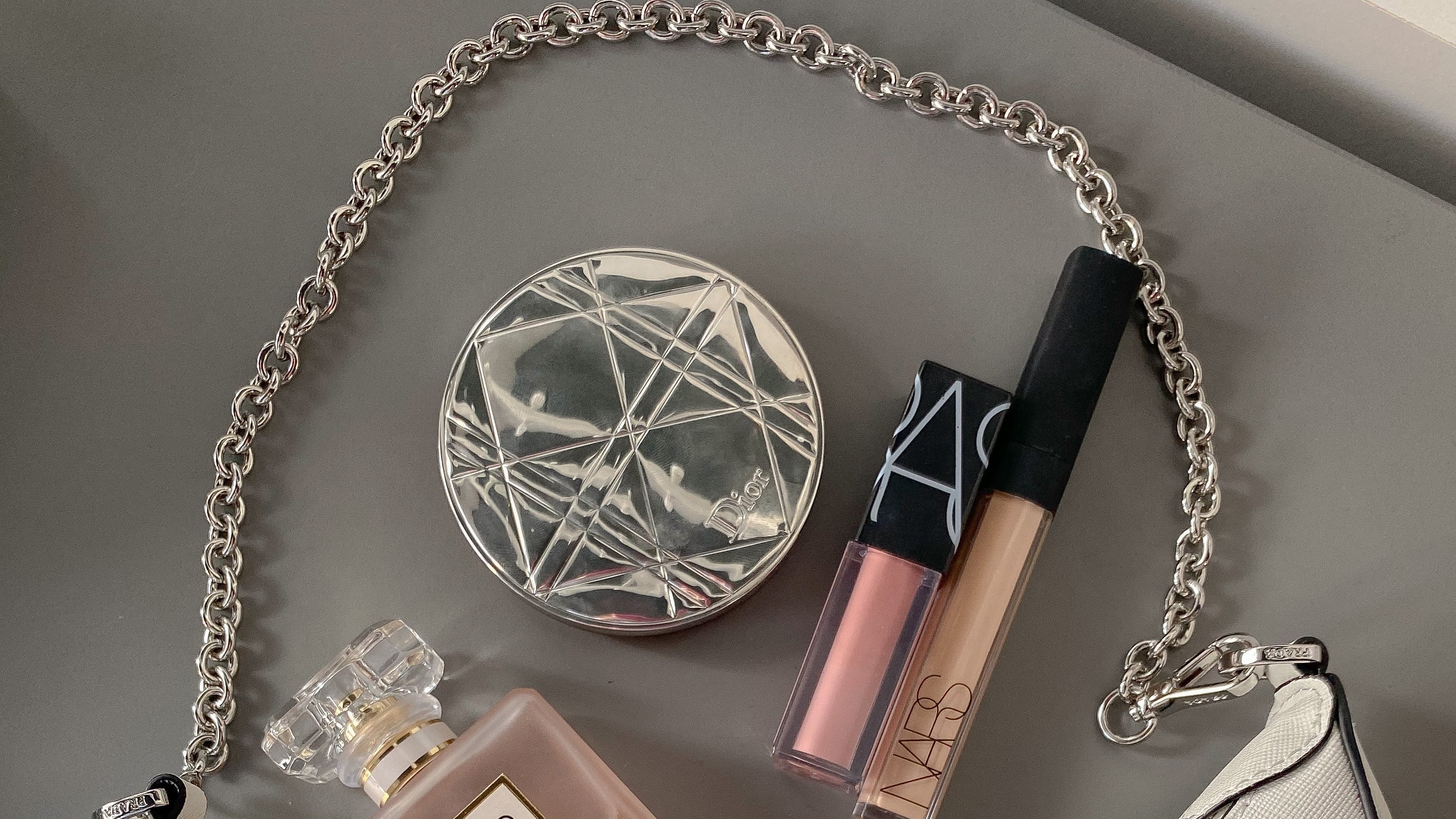 Bolsa da Prada com perfume e maquiagens