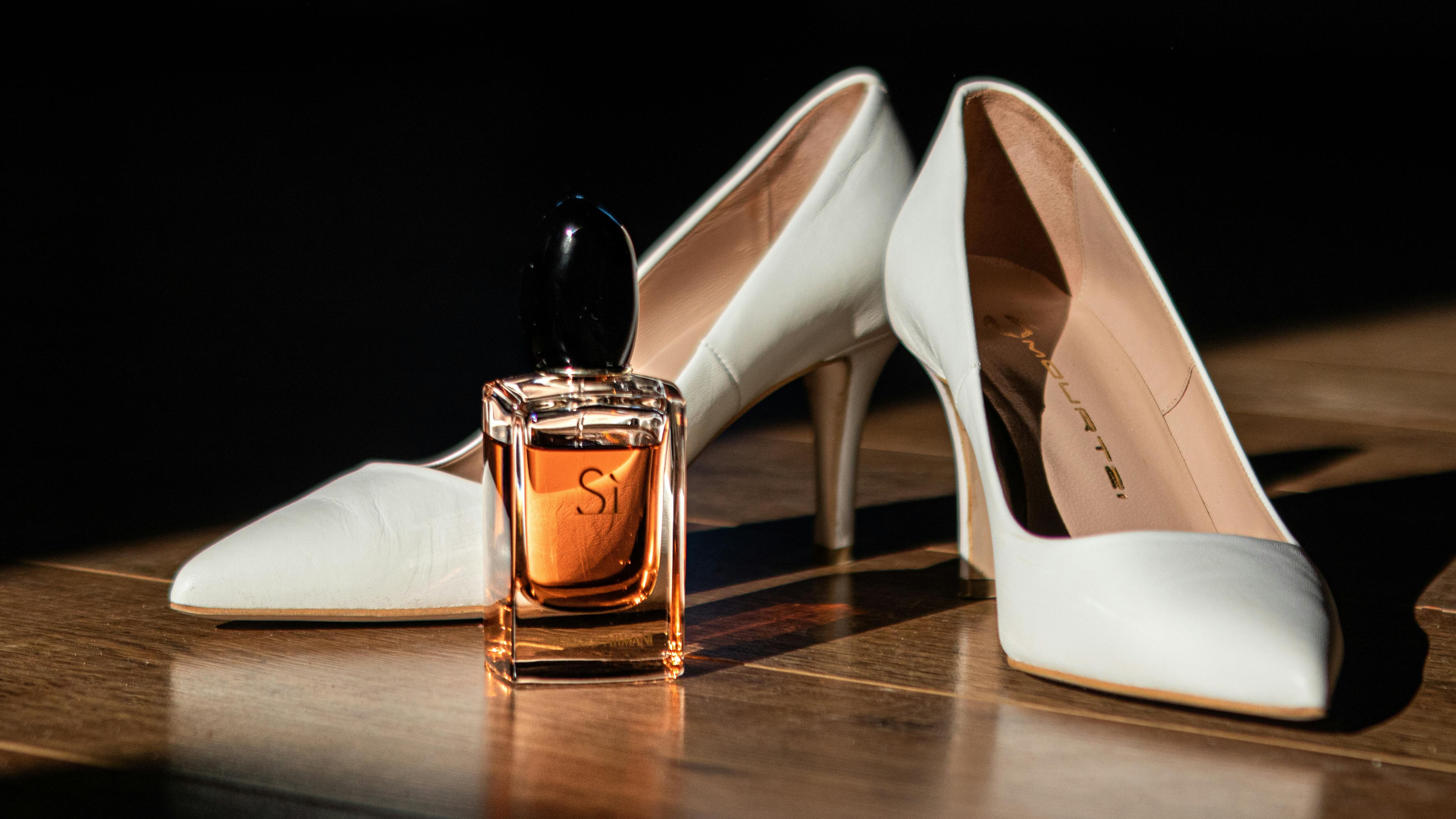 Frasco de perfume Sí ao lado de salto alto branco