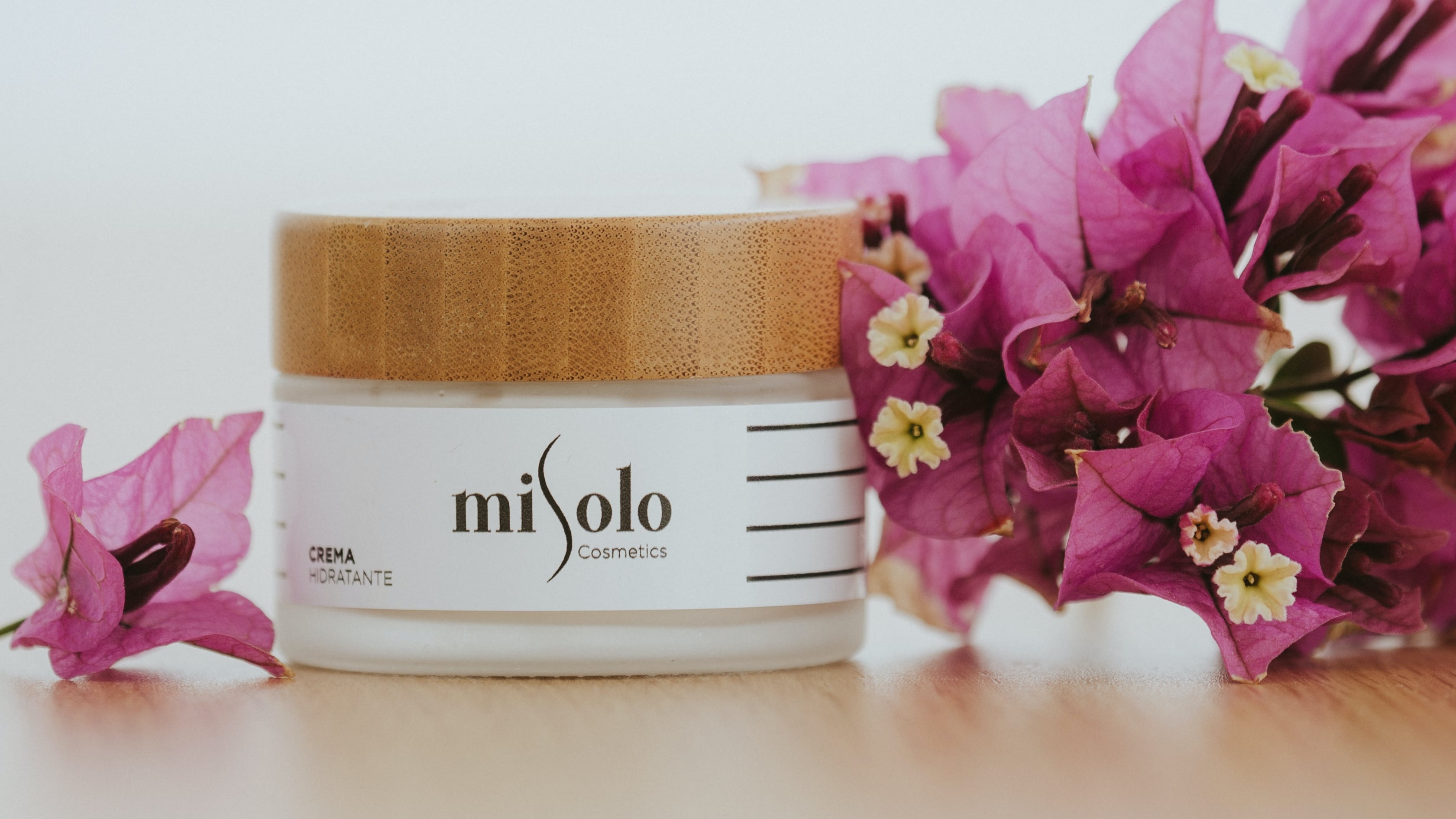 Pote de hidratante ao lado de flores rosas
