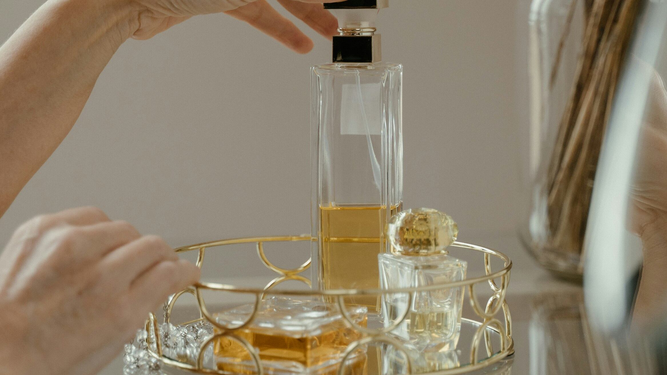 Mão feminina pegando frasco de perfume