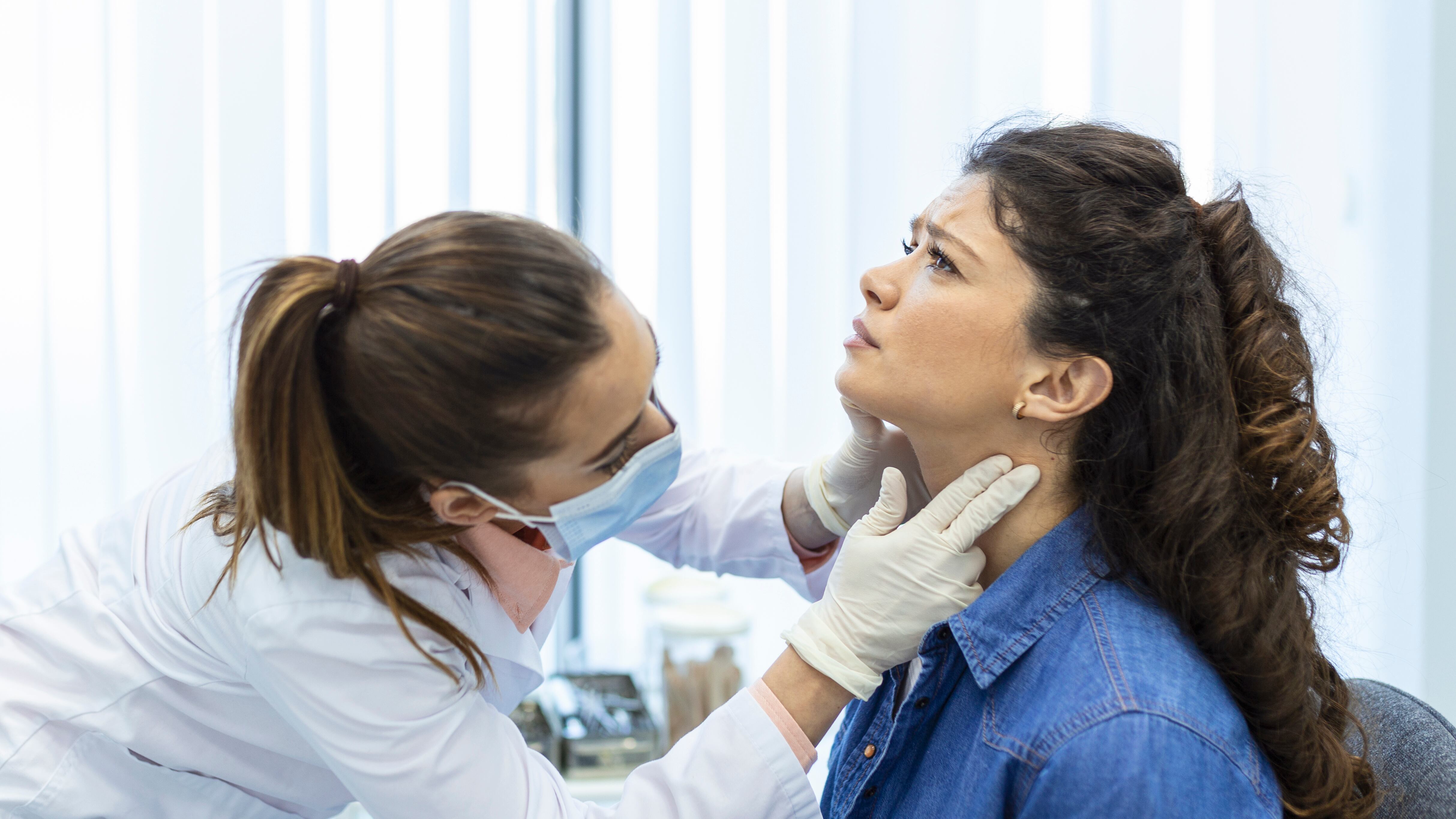 Mulher com dor na garganta sendo consultada por médica